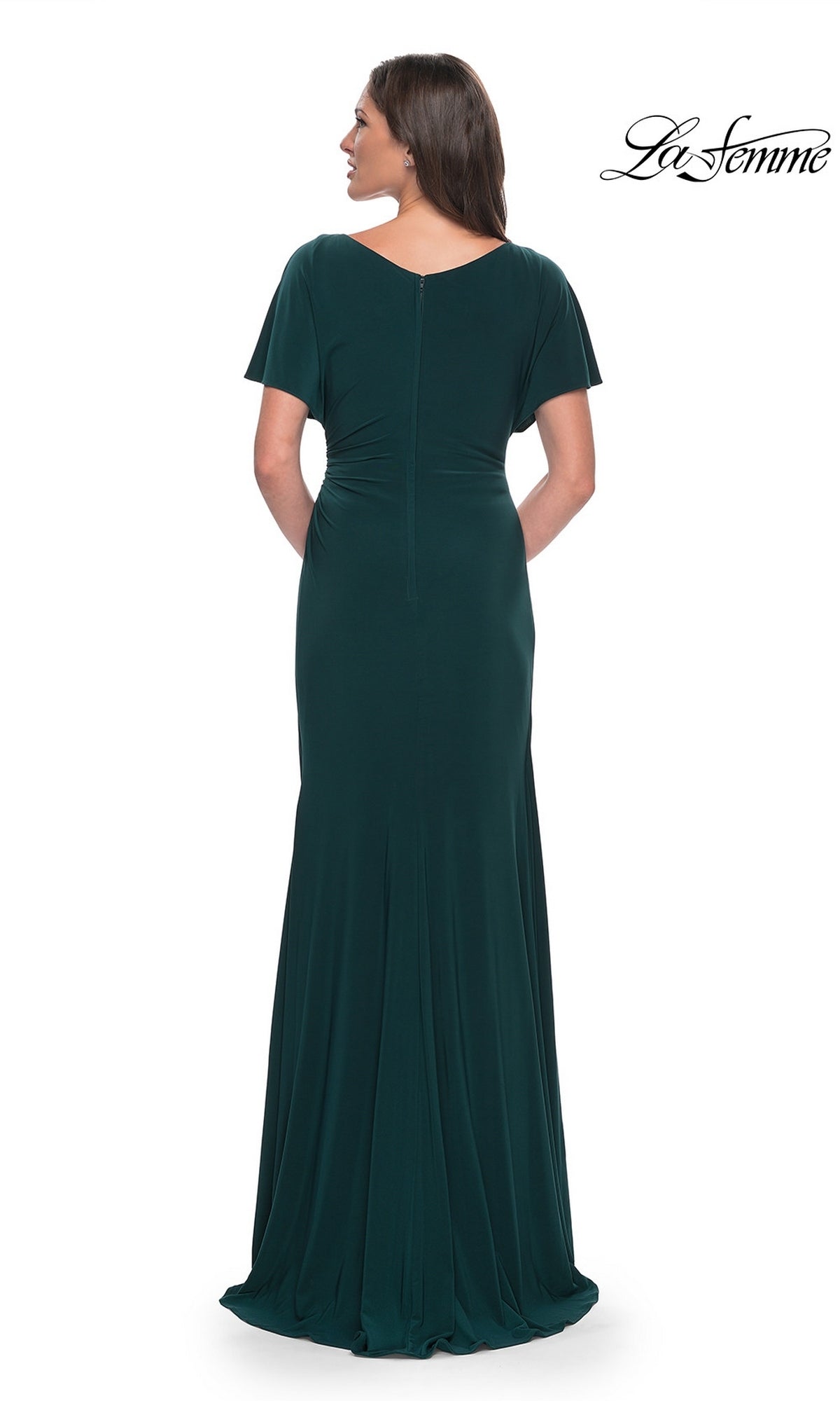 A woman seen from behind wearing a floor-length, dark green jersey La Femme 29997 formal dress with short flutter sleeves and a V-neckline.