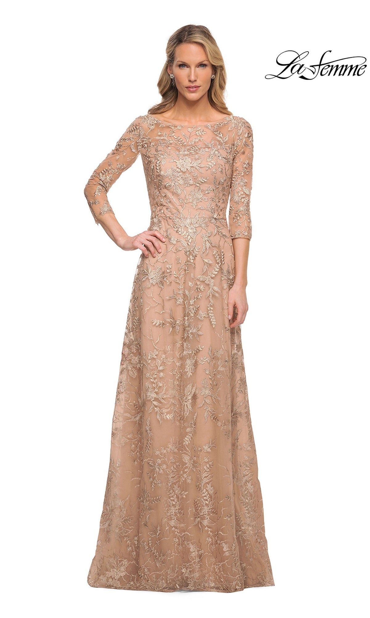 A woman wears the Long Formal Dress: La Femme 30021, a long, nude-gold formal dress with three-quarter sleeves and delicate floral lace embroidery.