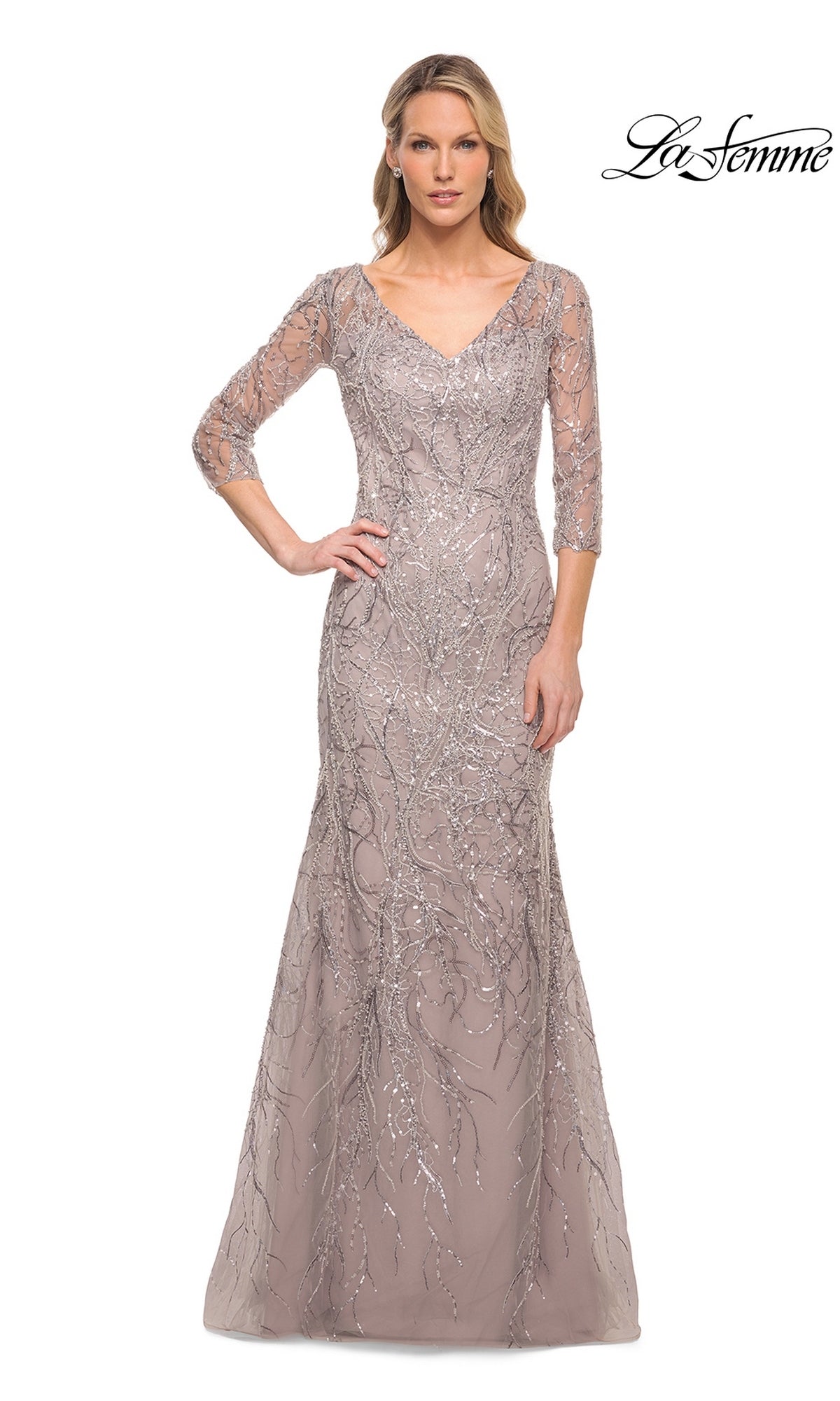 A woman wears a taupe-colored Long Formal Dress: La Femme 30044, a modest style with a V-neckline, three-quarter length sleeves, and silver sequined tree-branch patterns.
