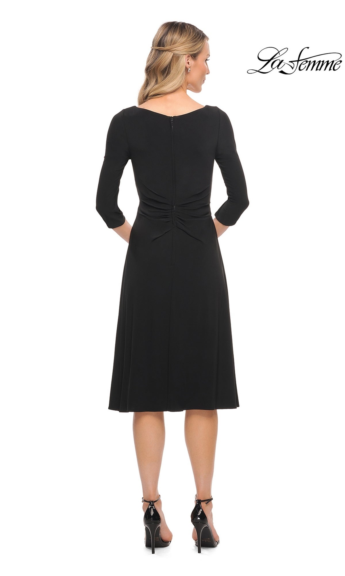 Back view of a woman wearing a black Midi Wedding Guest Dress: La Femme 30069, a midi-length fit-and-flare dress with three-quarter sleeves, gathered waist, and black heeled sandals.
