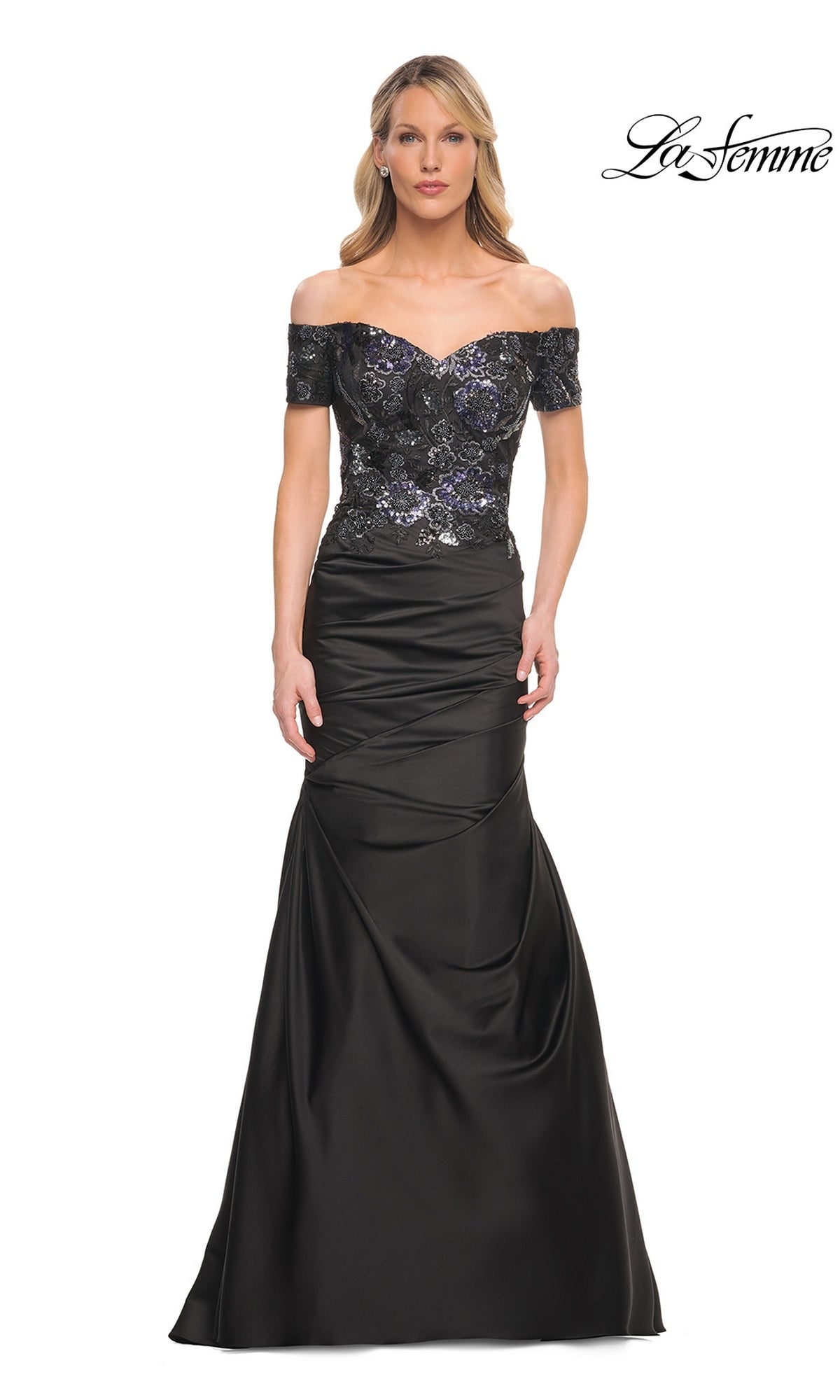 A woman wearing a black Long Formal Dress: La Femme 30404, featuring an off-the-shoulder mermaid silhouette with a sequined bodice and a floor-length skirt.