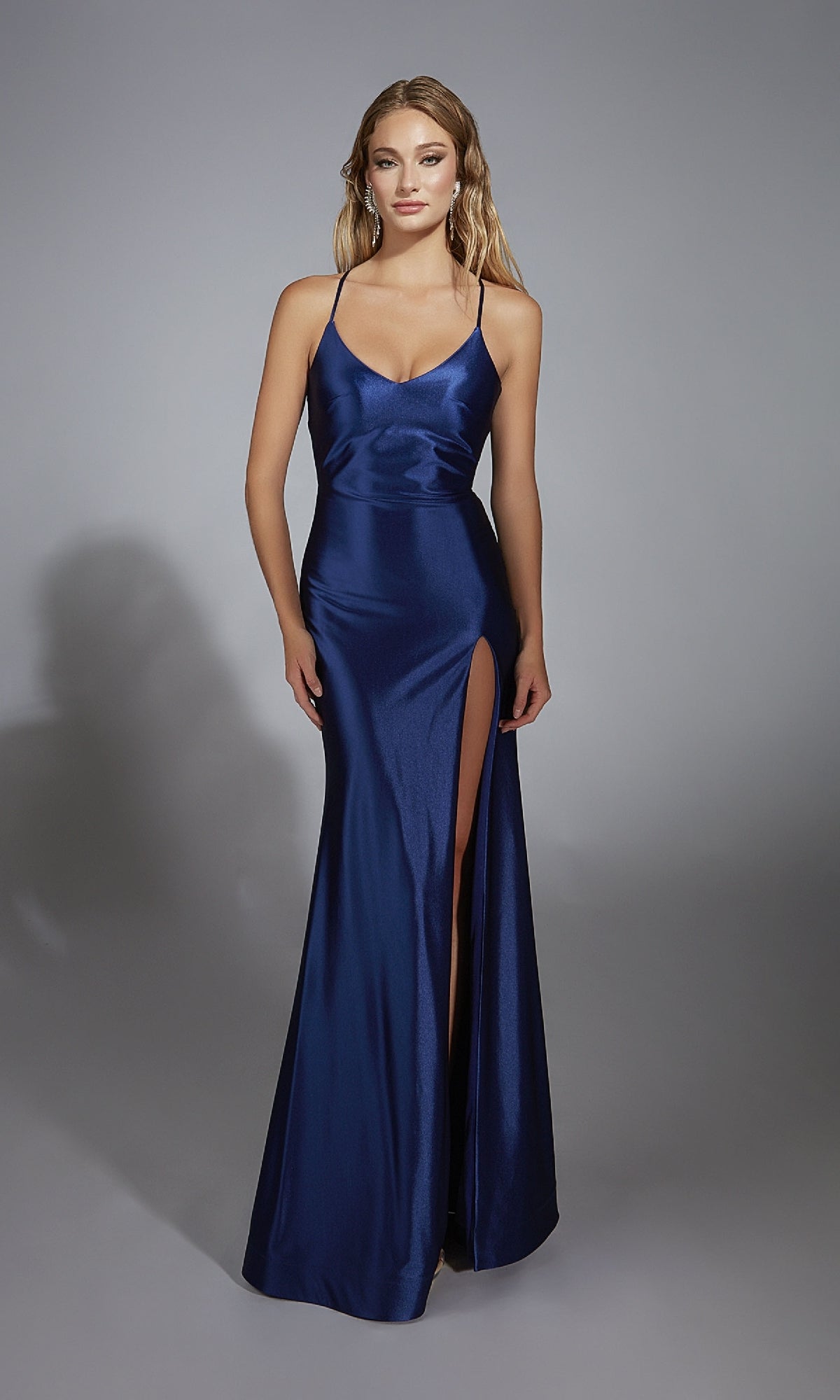 A woman models the Long Fitted Prom Dress: Aerie Couture 305—a navy blue satin gown with thin straps, thigh-high slit, floor-length skirt, and elegant open back—posing against a plain gray background.