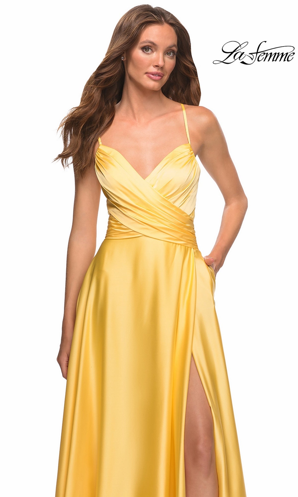 Woman wearing a bright yellow satin Long Prom Dress: La Femme 30662 with a V-neckline, crossover bodice, and a side slit.