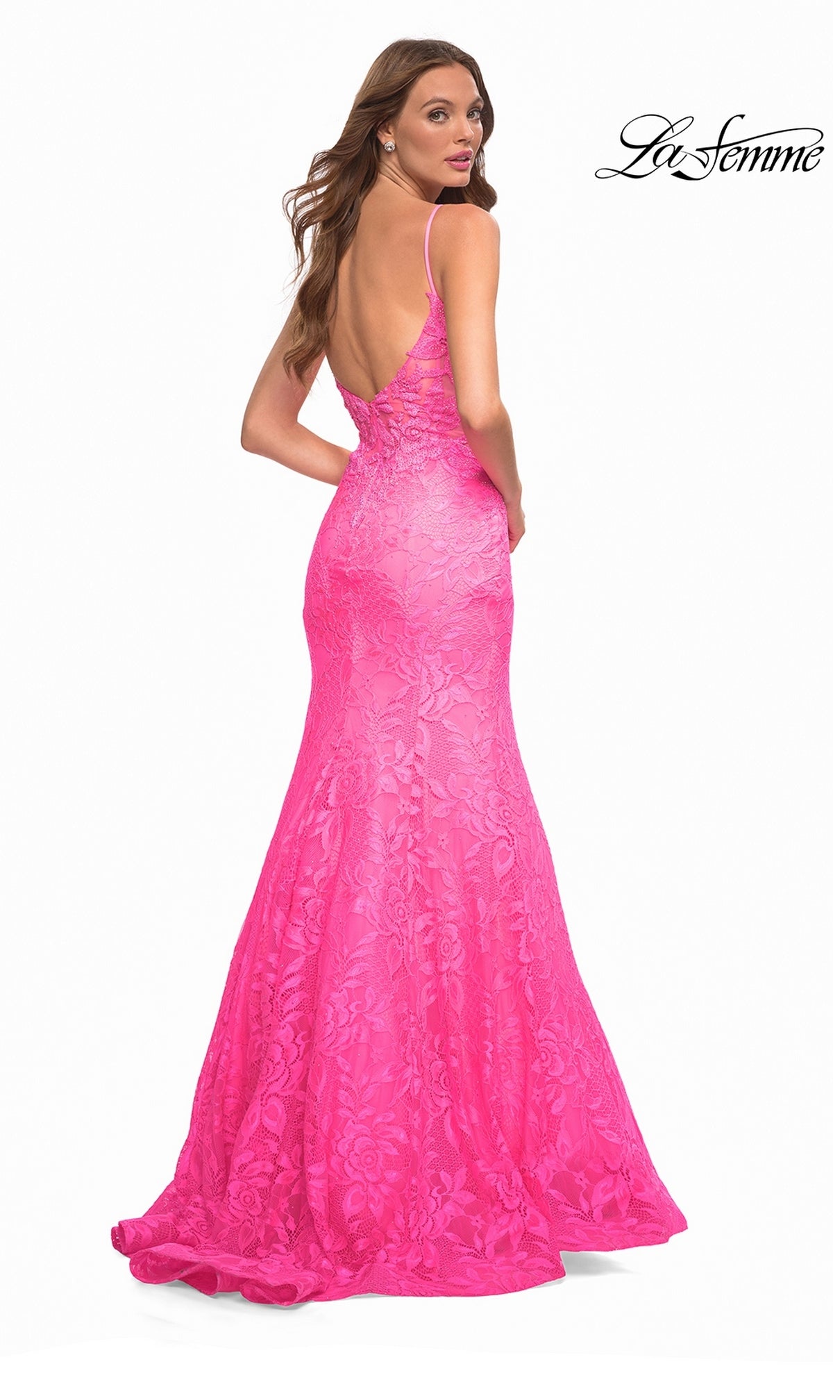 A woman wearing a La Femme 30663 floor-length, hot pink lace mermaid gown with a low back and thin spaghetti straps.