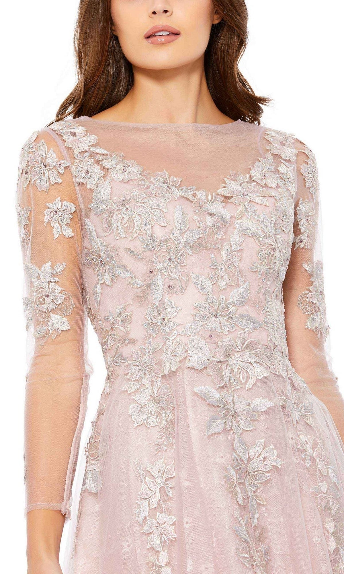 A woman wearing the Short Wedding Guest Dress 30681 by Mac Duggal, featuring a sheer, long sleeve pink A-line design with silver floral embroidery and a V-neckline.