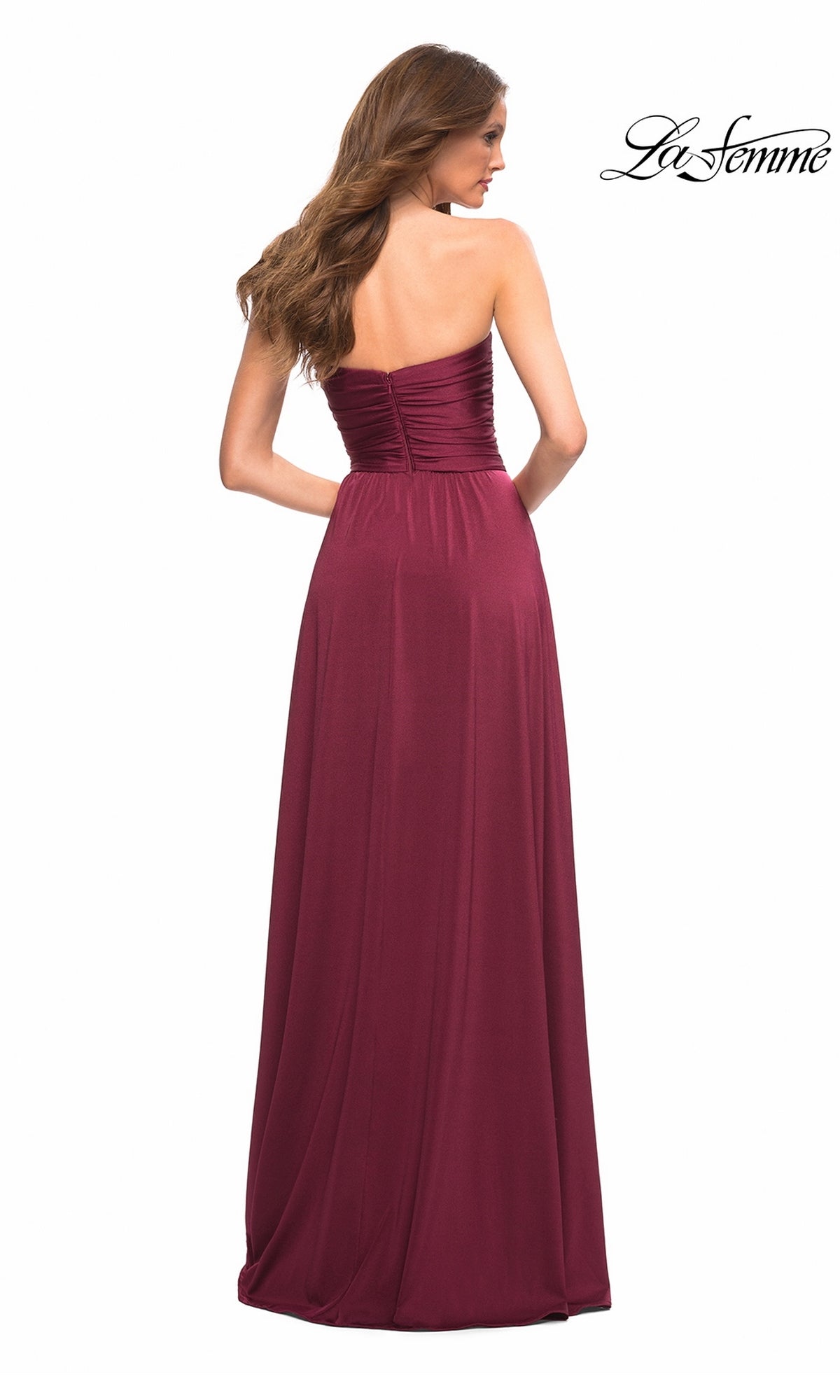Woman in the Long Prom Dress: La Femme 30700, a strapless burgundy jersey gown with a sweetheart neckline, stands with her back to the camera against a white background.
