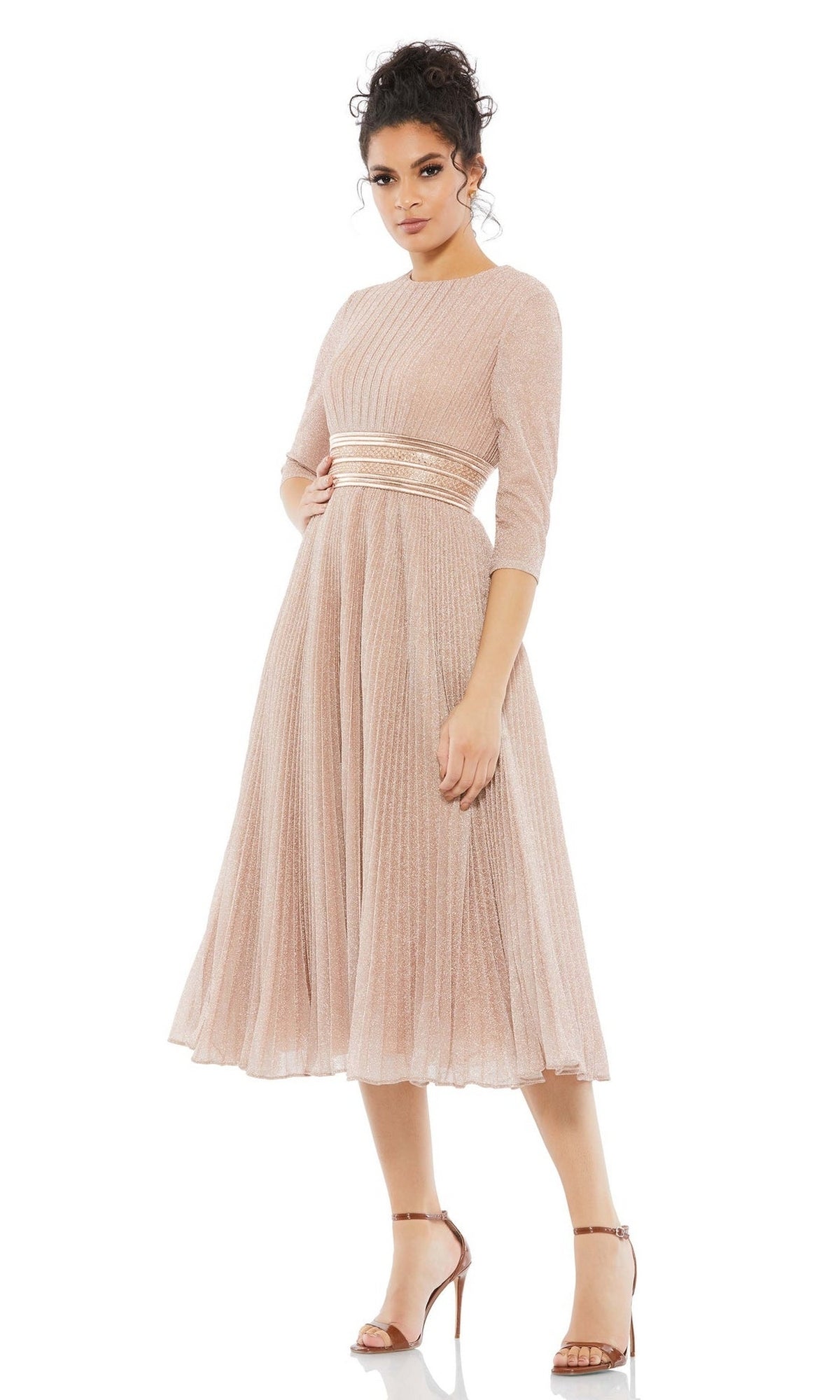 A woman wearing the Mac Duggal 30750 Tea-Length Wedding Guest Dress in light pink with pleats, three-quarter sleeves, and a fitted waist pairs it with strappy high-heeled sandals against a white background.