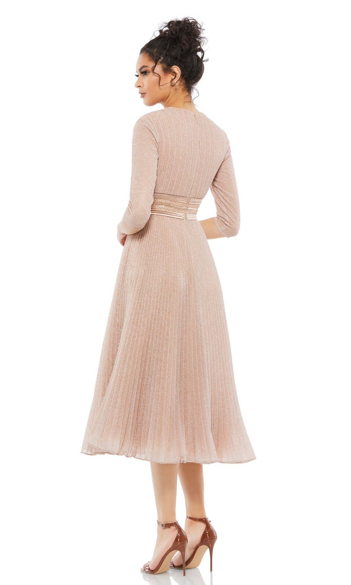 A woman faces away, wearing the Mac Duggal 30750 Tea-Length Wedding Guest Dress in light pink with long sleeves and pleats, paired with nude high-heeled sandals against a white background.