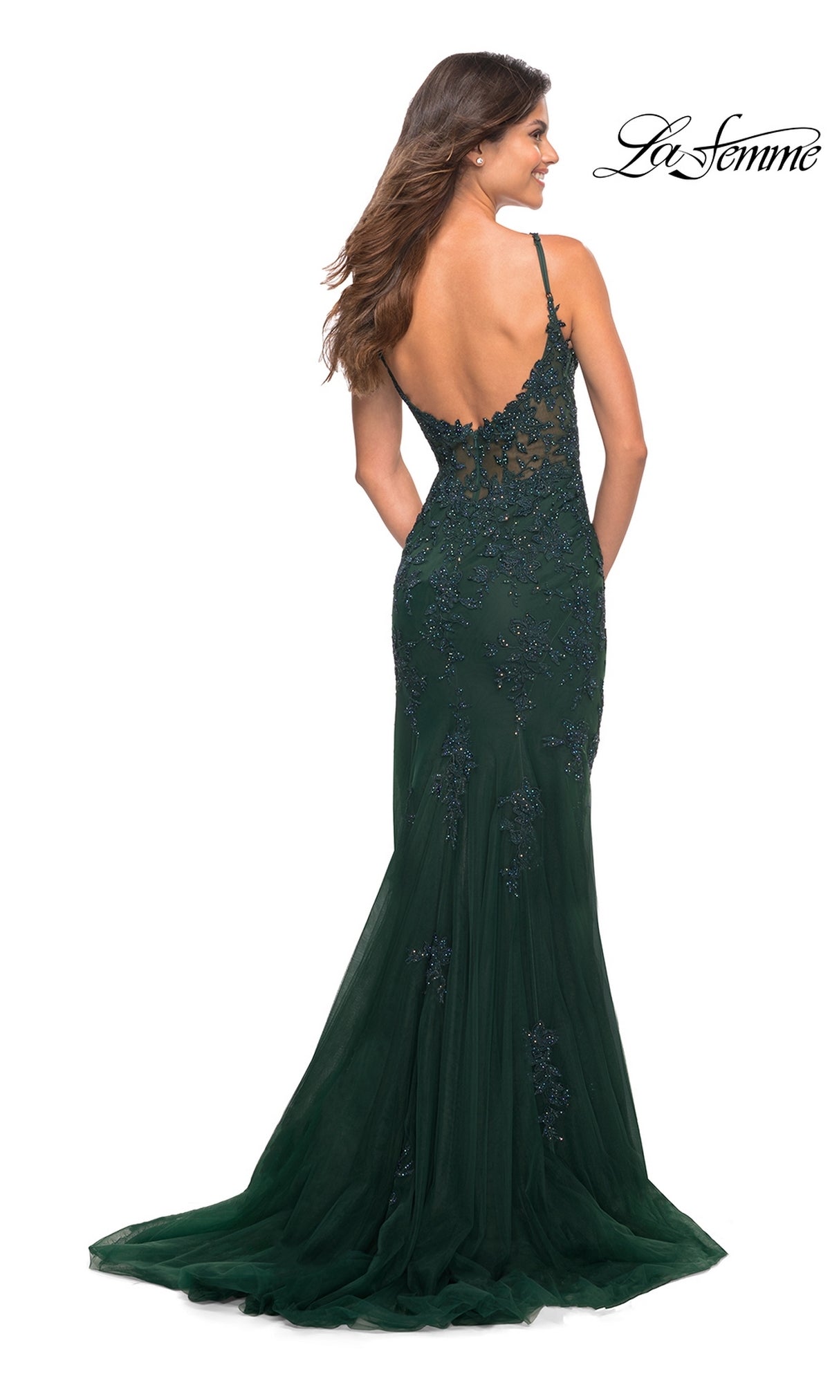 A woman stands with her back to the camera, wearing the La Femme Sheer-Corset-Bodice Long Prom Dress 30767—an elegant dark green gown with lace embroidery, beaded details, and an open back.