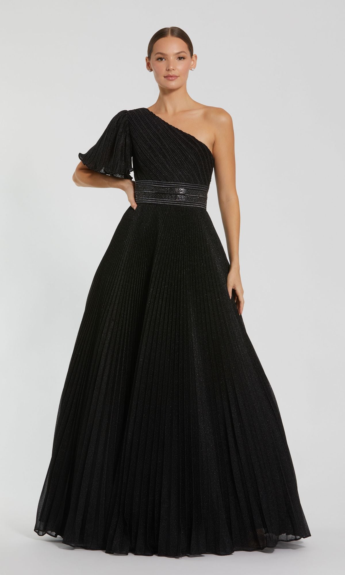 A woman stands against a plain white background wearing the Mac Duggal 30777, a one-sleeve black formal gown.
