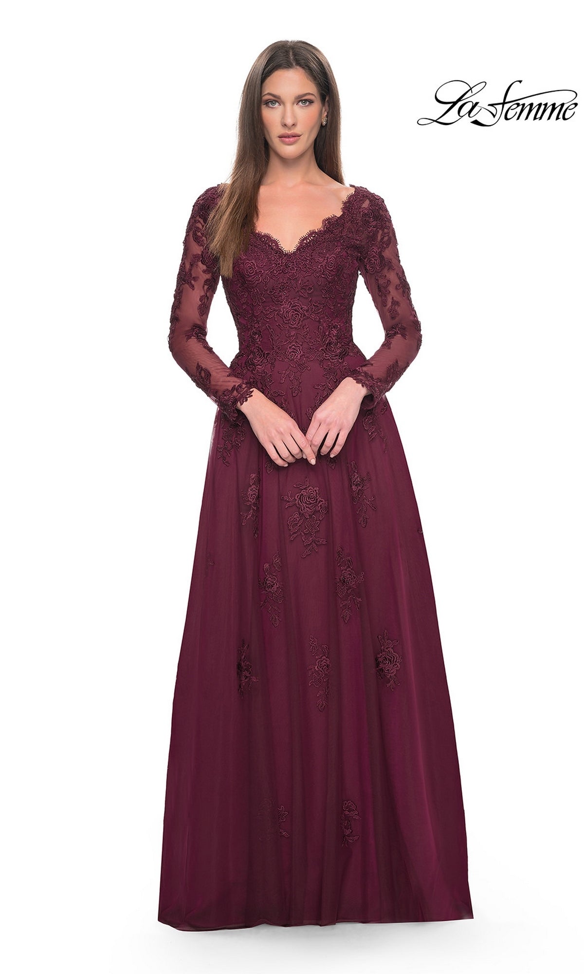 A woman wears the Long Formal Dress: La Femme 30795, a floor-length, deep burgundy gown with long sleeves, a V-neckline, and a tulle A-line skirt detailed with beaded lace appliques.
