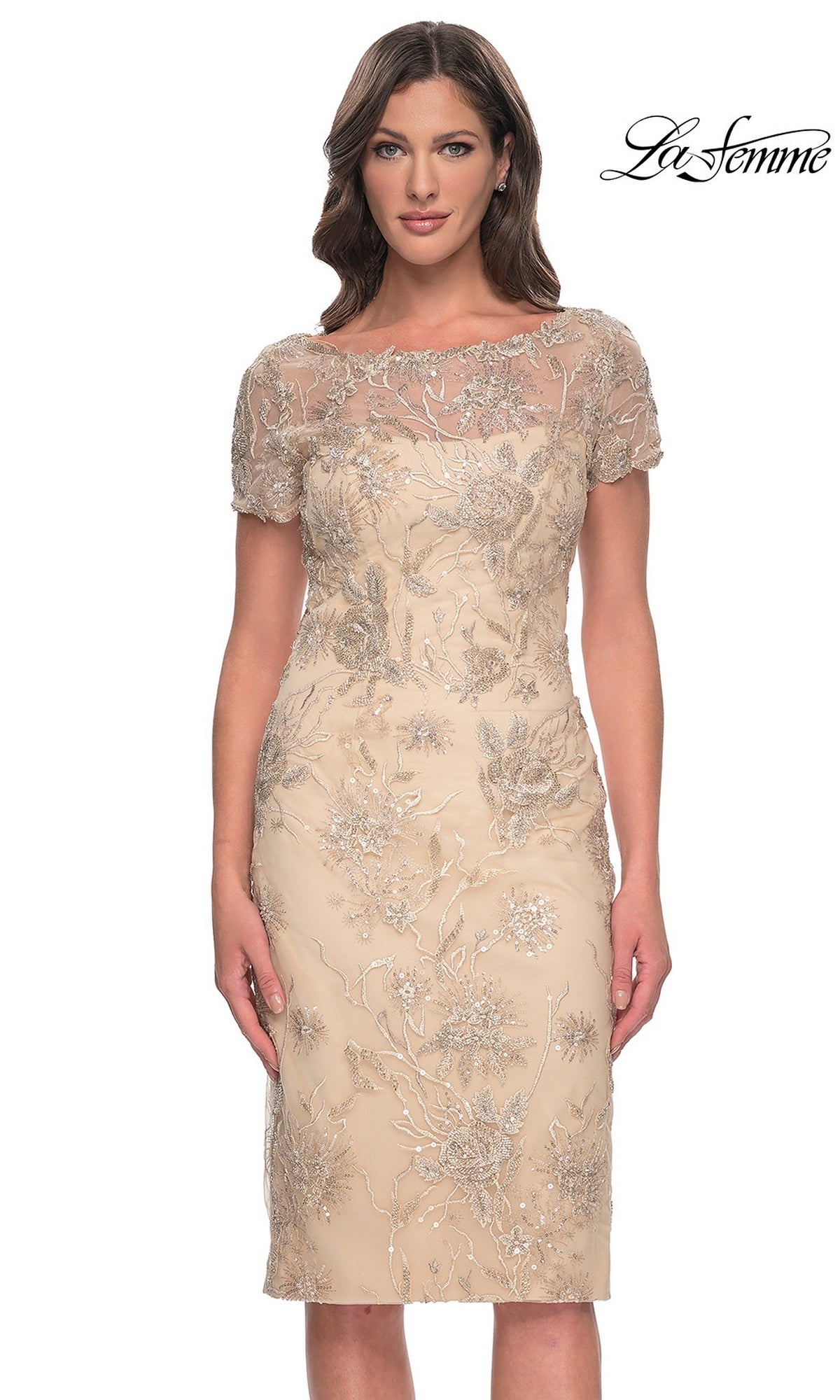 A woman wearing a knee-length, nude-colored La Femme 30801 wedding guest dress with short sleeves and intricate silver floral lace applique.