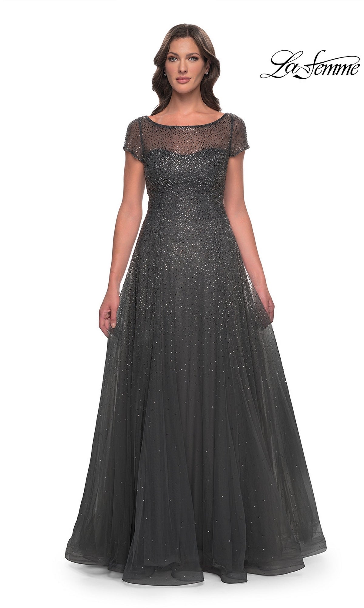 A woman wears a gunmetal-colored La Femme 30852 long formal dress featuring cap sleeves and a beaded, semi-sheer bodice.