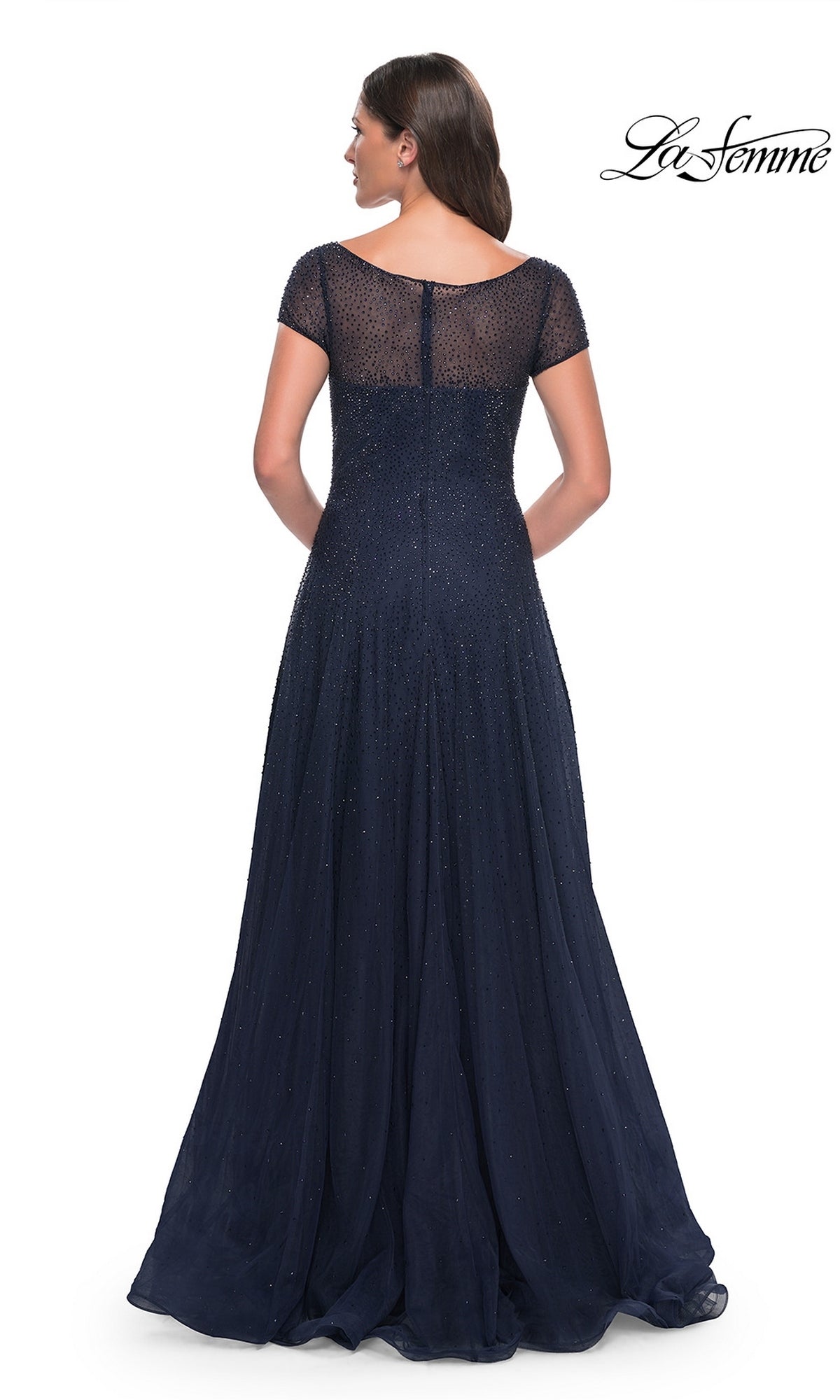 Back view of a woman wearing a floor-length navy blue La Femme 30852 formal dress with short sleeves and a sheer, rhinestone beaded bodice.