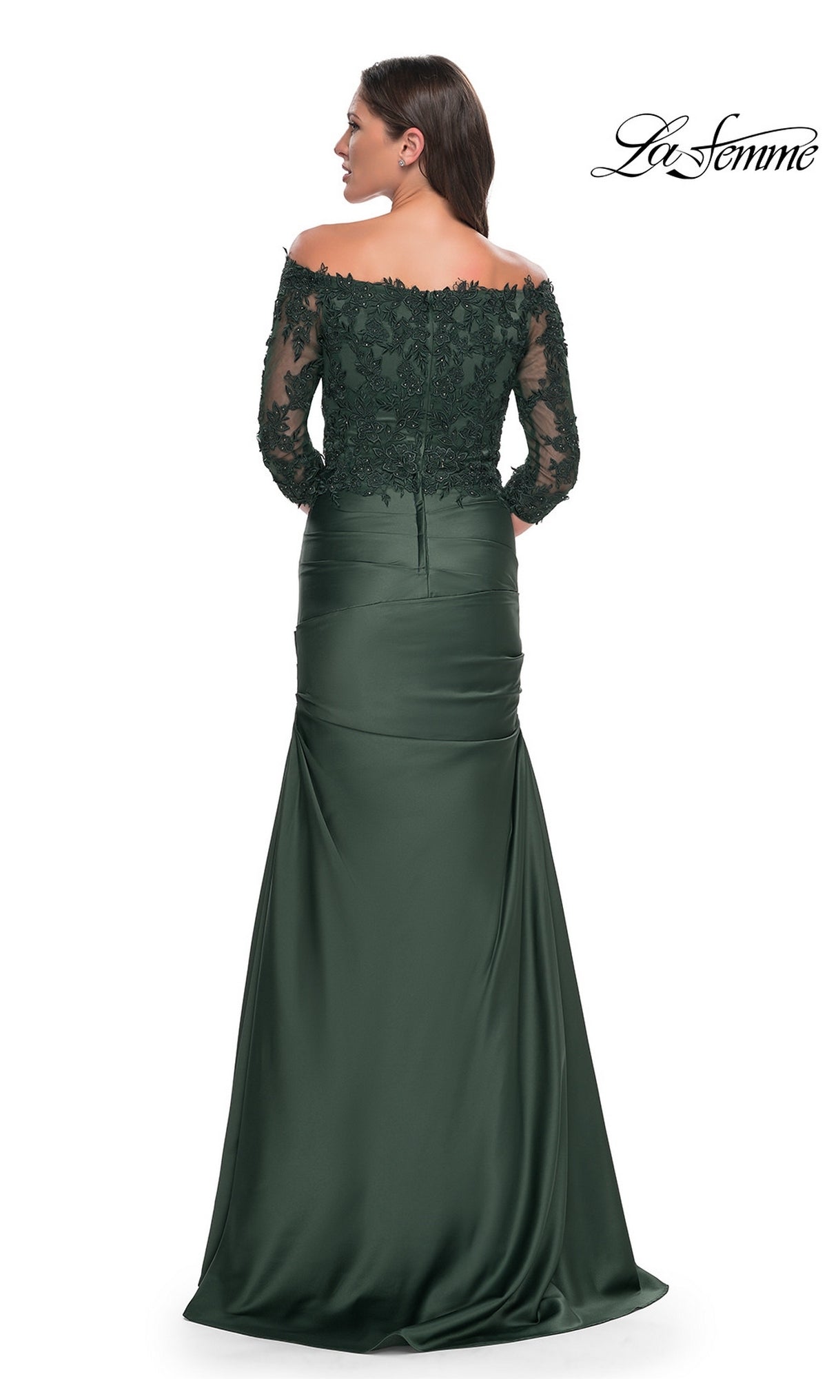 Woman wearing a La Femme 30853, an off-the-shoulder, dark green floor-length gown with a lace bodice, three-quarter length lace sleeves, and a draped trumpet skirt.
