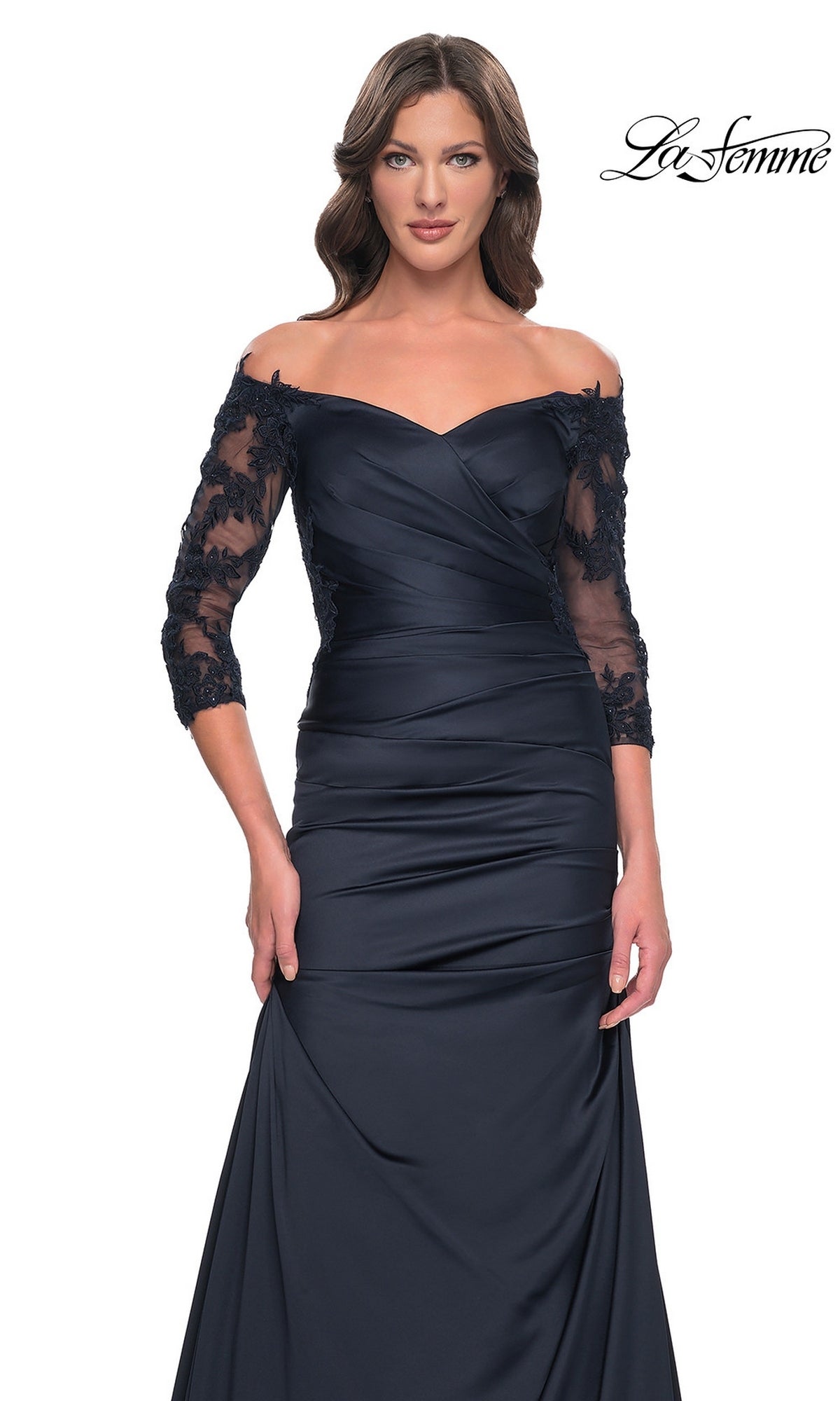 The La Femme 30853 is a dark navy off-the-shoulder formal gown with a ruched bodice, three-quarter length sheer lace sleeves, and a long trumpet skirt.