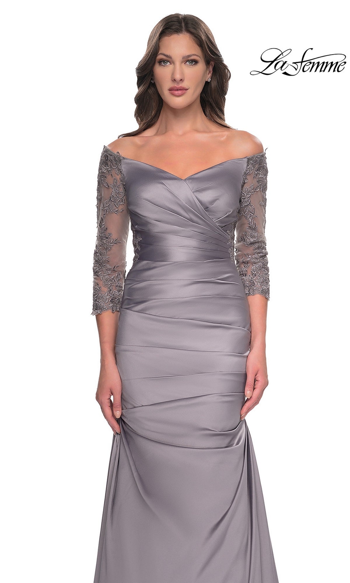 A woman wears a La Femme 30853 long formal dress featuring an off-the-shoulder grey design with long, sheer lace sleeves, a pleated bodice, and a trumpet skirt.