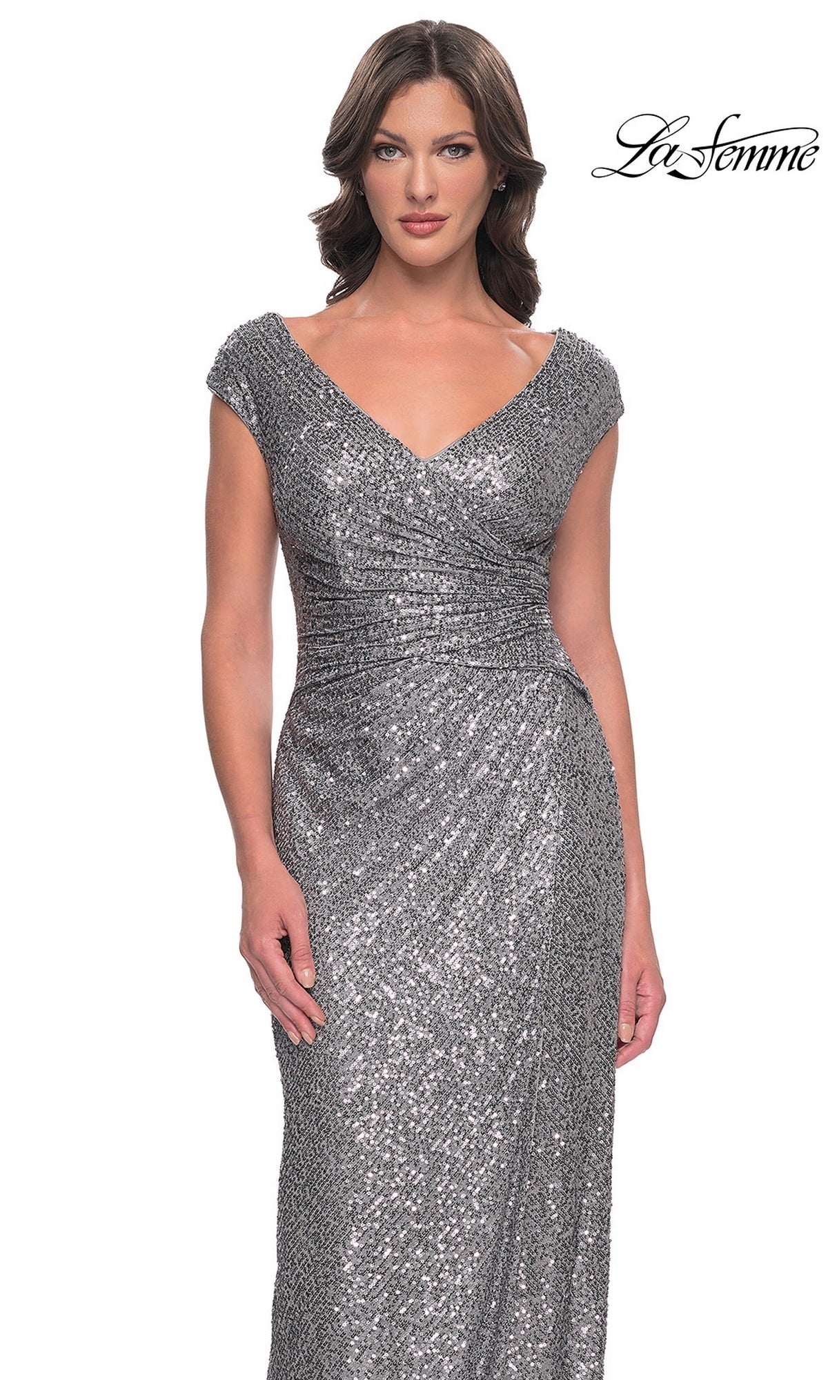 A woman wearing a Long Formal Dress: La Femme 30865, a floor-length, silver sequin V-neck dress with cap sleeves and a ruched waist in a sheath silhouette.