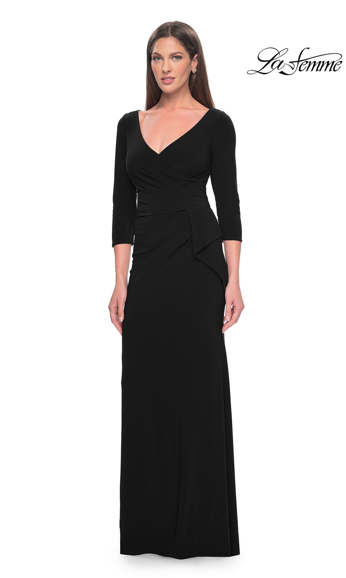 A woman stands against a white background wearing the La Femme Sleeved Simple Jersey Formal Dress 30967, a long black V-neck design with three-quarter sleeves. The
