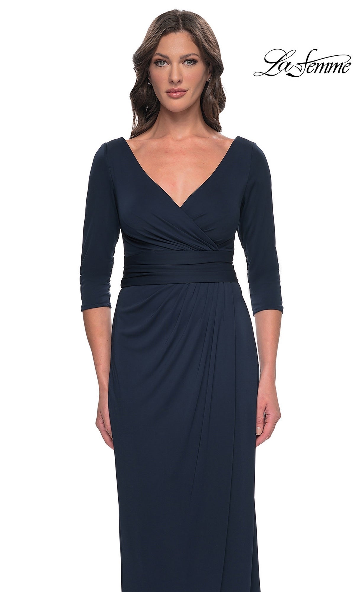 A woman wears a navy blue, long-sleeved faux wrap Long Formal Dress: La Femme 31014 featuring a V-neck and a fitted waist.