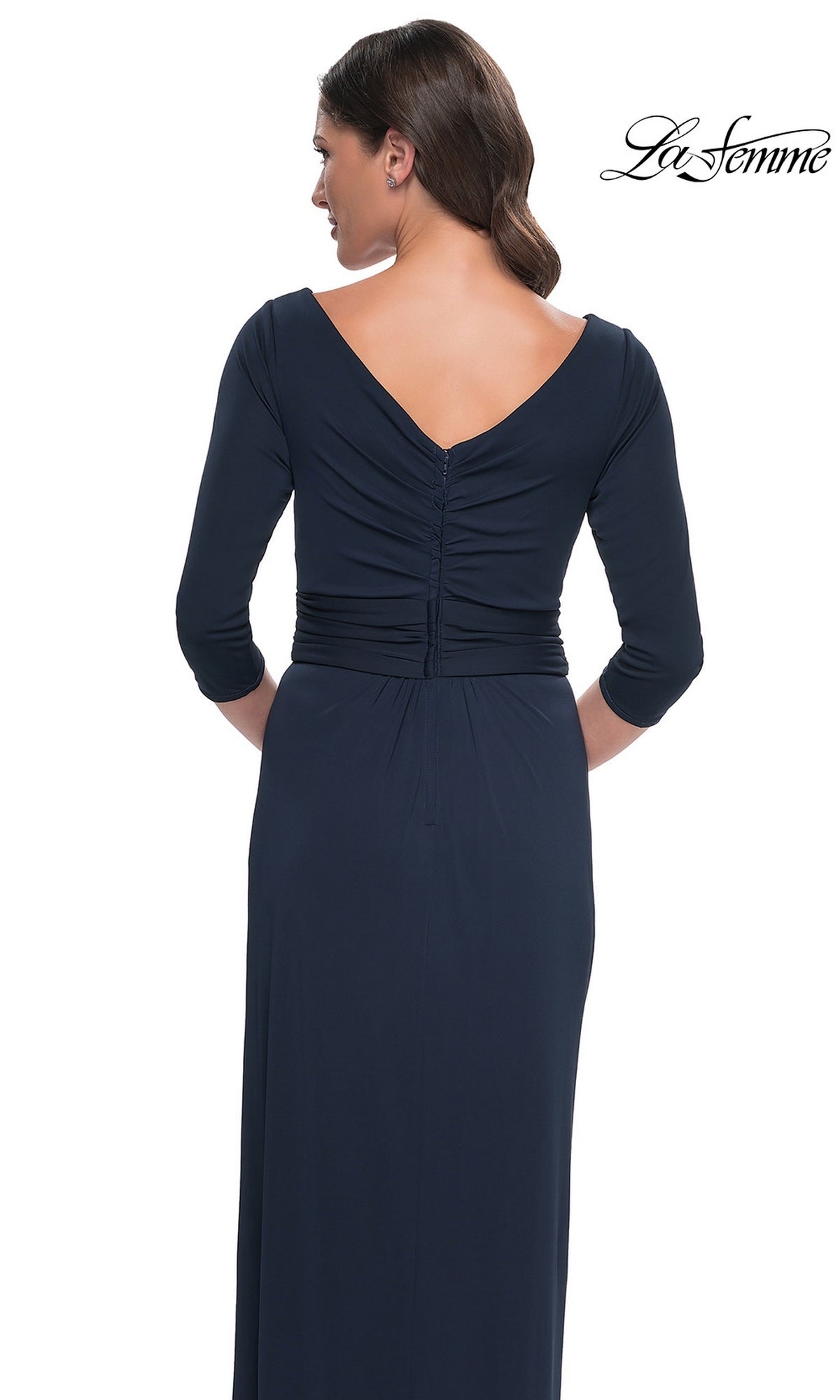 Back view of a woman wearing the La Femme 31014, a navy blue modest formal dress featuring a floor-length faux wrap evening gown design with three-quarter sleeves, a V-neckline, and ruched back detailing.