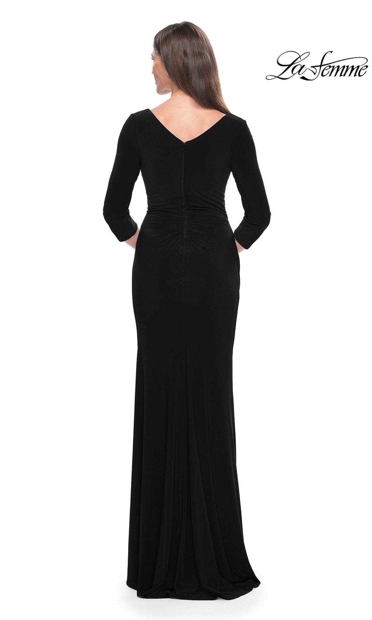 A woman stands with her back to the camera in a La Femme Long-Sleeve Fitted Formal Dress 31020, black with a v-neck and three-quarter sleeves, against a white background. The