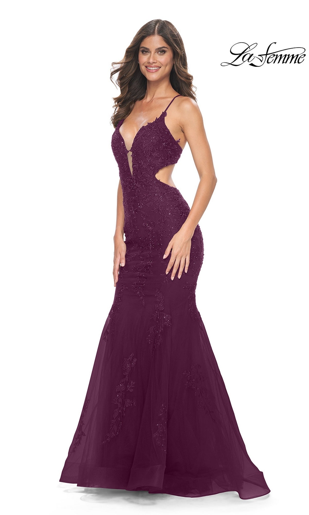 A woman wearing a deep purple, floor-length La Femme 31132 mermaid gown with a plunging neckline, cutout sides, and beaded lace appliques.