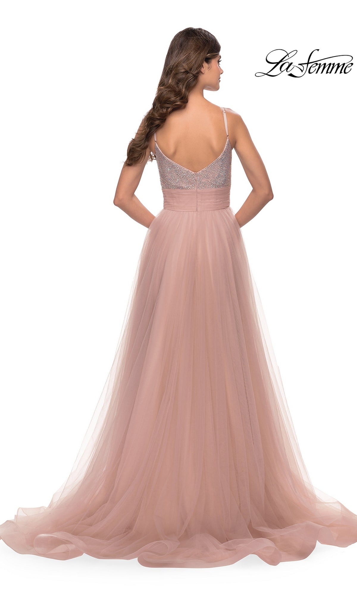 A woman is seen from the back in the Beaded-Bodice Tulle Prom Ball Gown 31238, a blush pink La Femme dress with a fitted, beaded bodice, spaghetti straps, v-neckline, and a flowy tulle skirt for an elegant look.