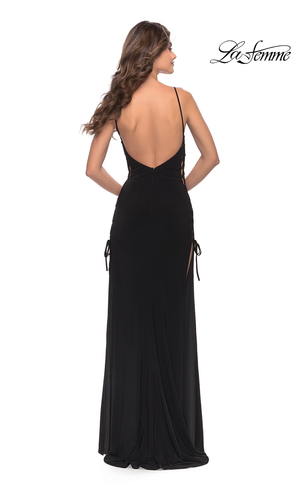 Back view of a woman in a Long Prom Dress: La Femme 31311, featuring a floor-length black matte jersey design with a low back, thin straps, and side lace-up details.