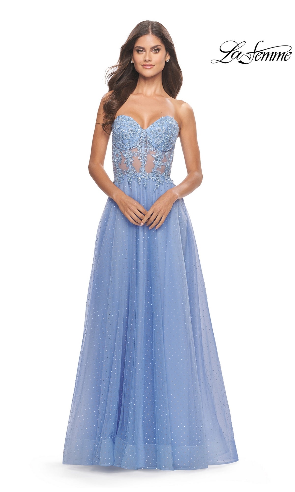 A woman wears the La Femme Strapless Sheer-Waist Prom Dress 31367 in light blue, featuring lace embroidery on the bodice and a flowing A-line tulle skirt with sheer panels.