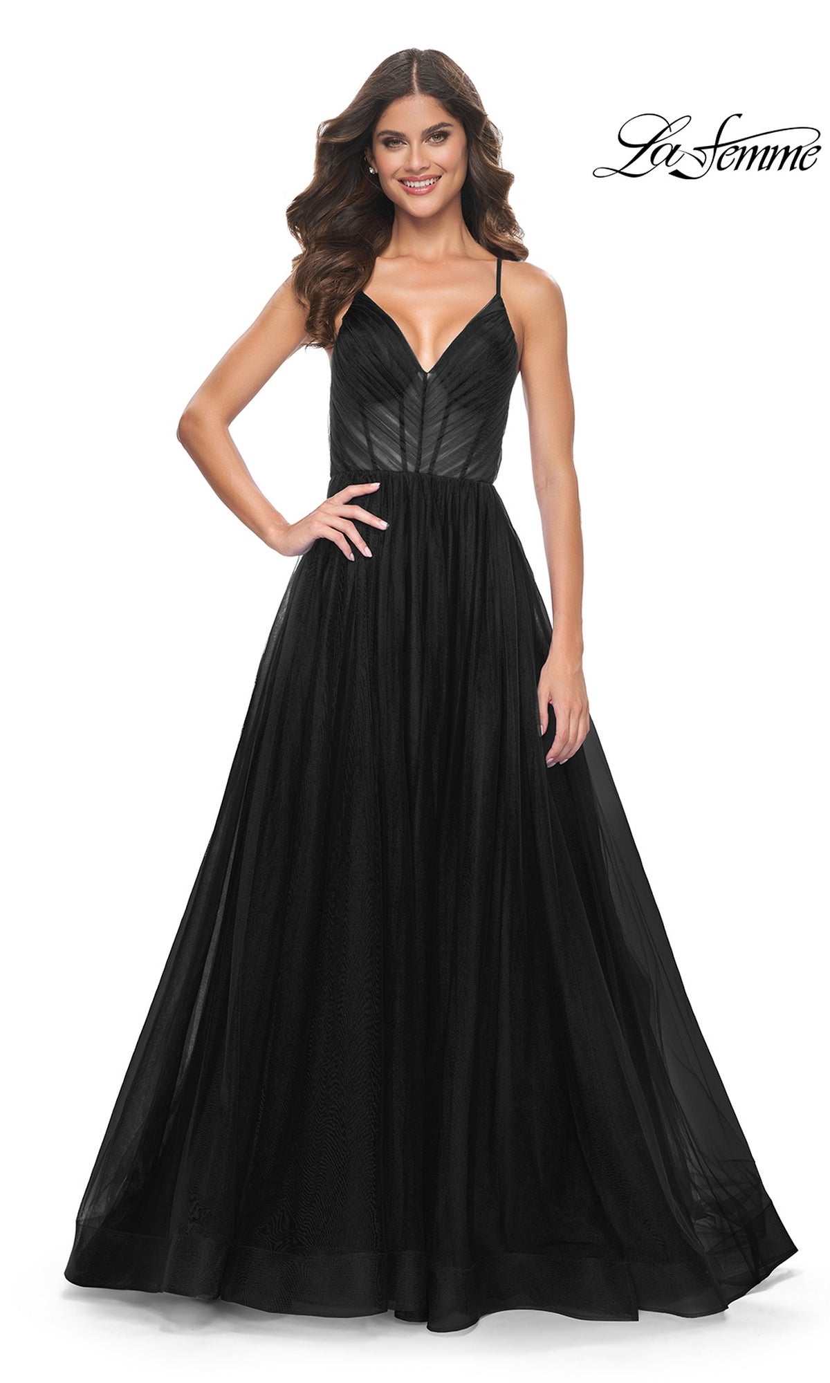 Woman in a La Femme Sheer-Waist Long Prom Ball Gown 31457, featuring thin straps, a fitted bodice, and a flowing skirt for an elegant A-line silhouette, standing and smiling against a plain white background.