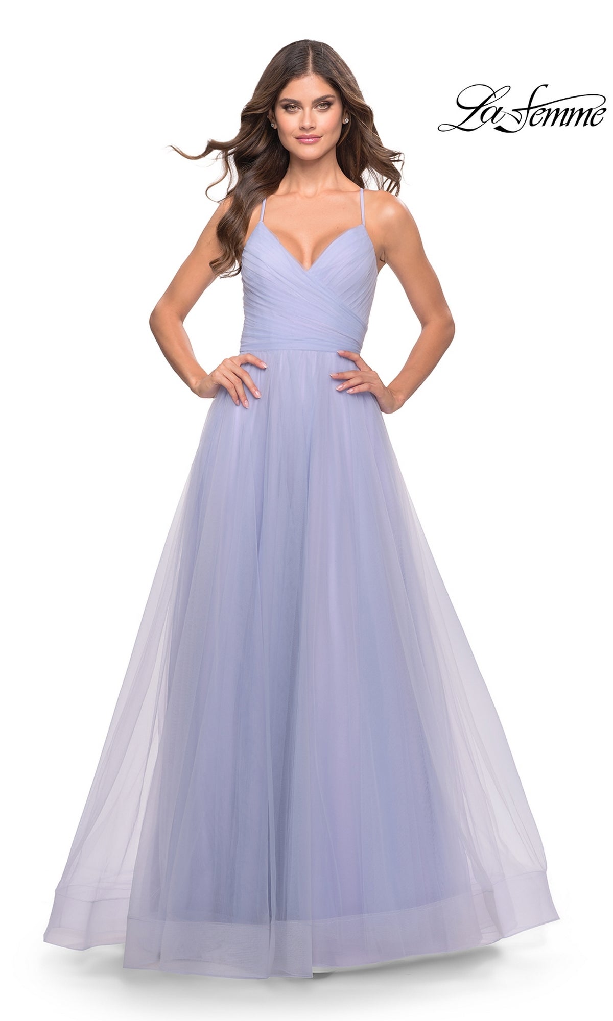 A woman wears the La Femme Wrap-Bodice Long A-Line Prom Dress 31501 in light lavender, featuring spaghetti straps, a fitted ruched bodice, and flowing ethereal tulle. The La Femme logo appears in the top right corner.