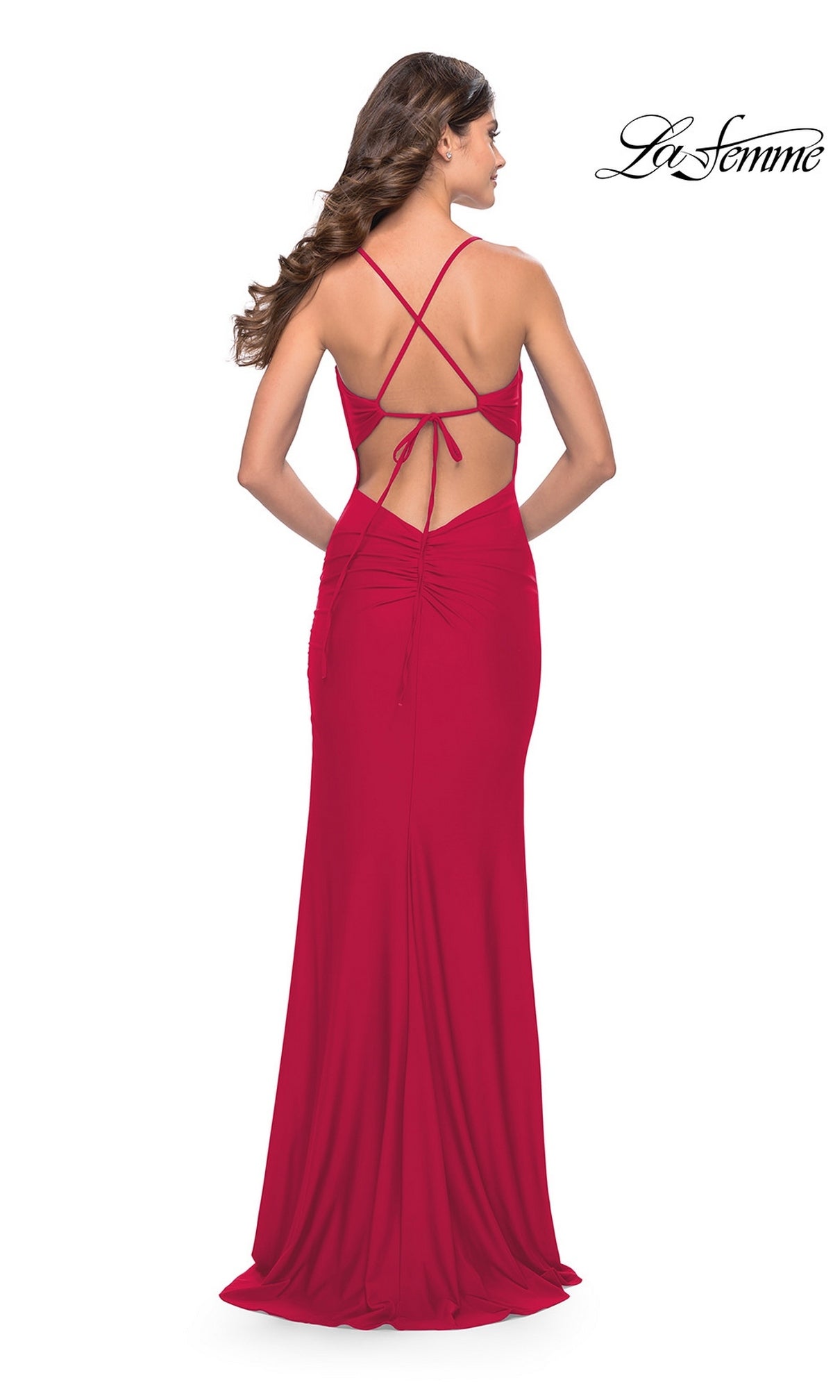 A woman stands facing away from the camera, wearing the La Femme 31516 front-knot long prom dress in red, featuring a floor-length silhouette, open back with thin crisscross straps, and subtle ruching.
