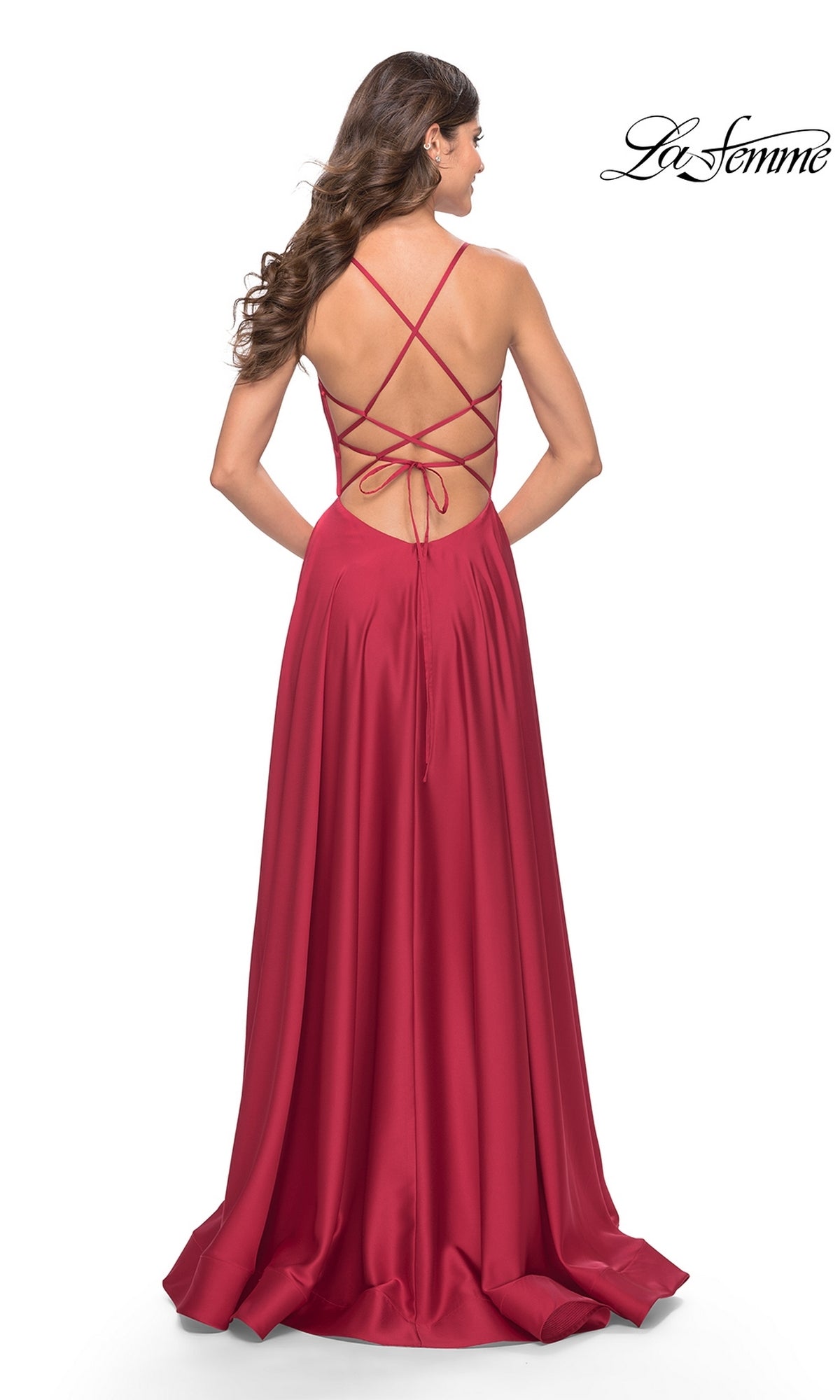A woman faces away from the camera, wearing the La Femme 31533—a deep V-neck, long A-line prom dress—featuring bold red satin, an open back with crisscross straps, and a chic silhouette.