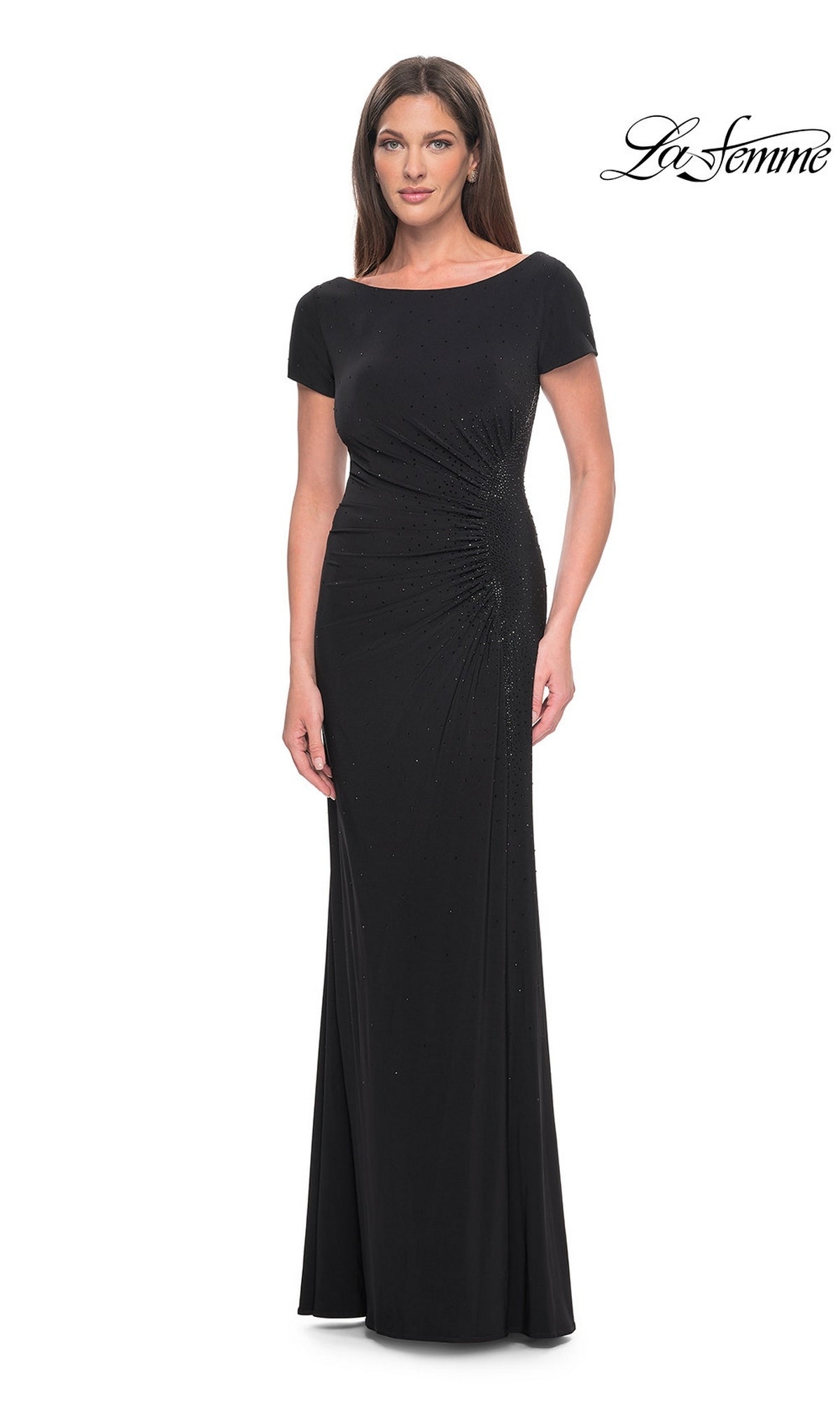 A woman wears a black, floor-length, short-sleeved La Femme 31773 formal dress featuring side-ruched detailing and subtle rhinestone embellishments.