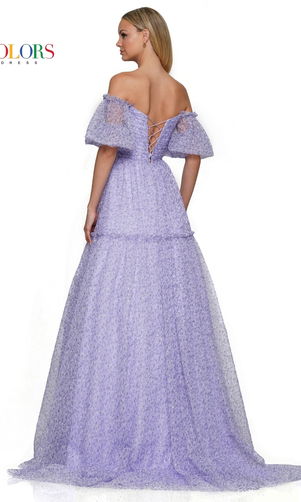A woman faces away from the camera wearing the Colors Dress Long A-Line Prom Dress 3190, featuring light purple fabric, puff sleeves, an off-the-shoulder neckline, and a lace-up back.