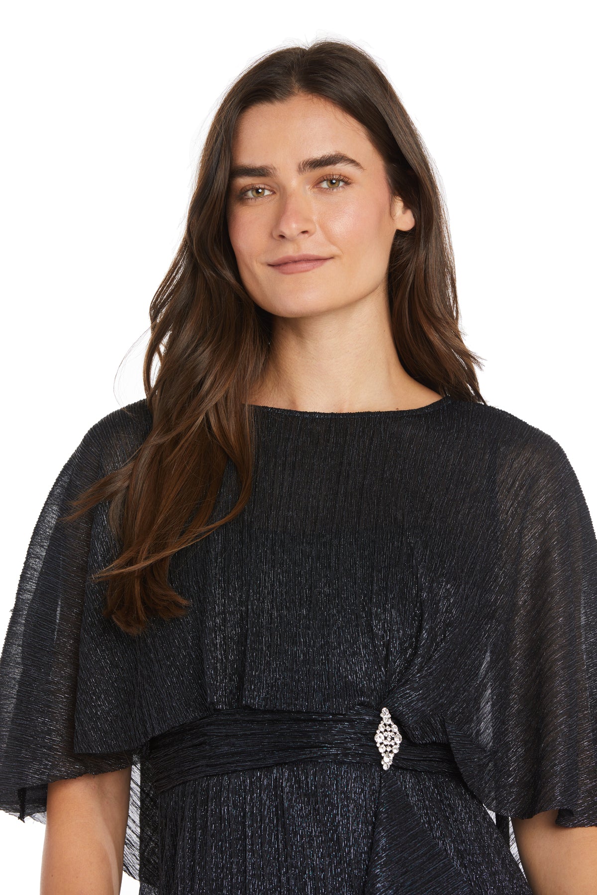 A woman with long brown hair models the R&M Richards 3195P Caped Knee-Length Party Dress, featuring short wide sleeves and a decorative waist brooch, standing against a white background.