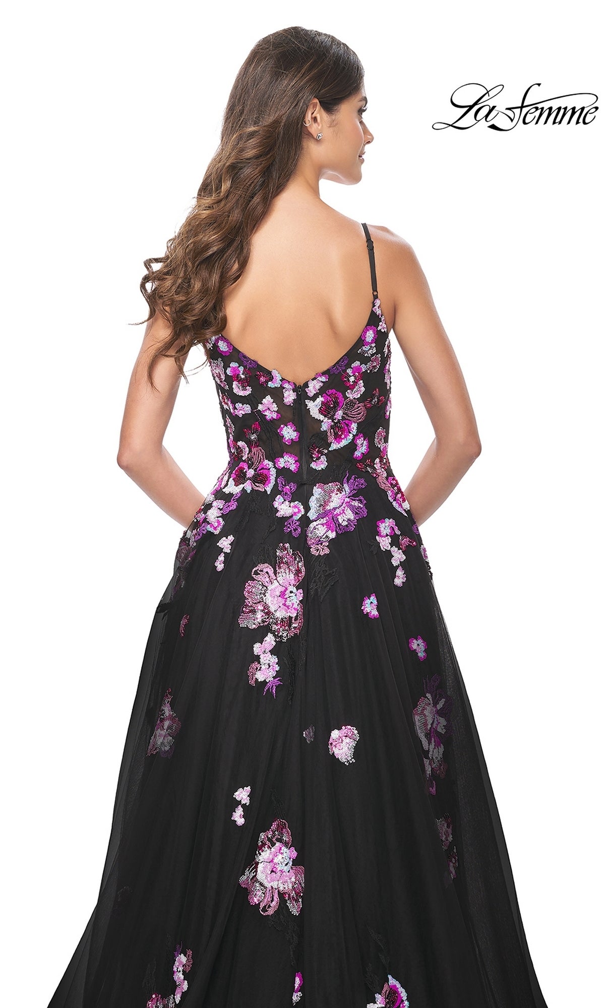 A woman with long wavy hair is seen from the back wearing the La Femme Purple-Floral Long Black Prom Dress 32030, featuring thin straps, pink and purple sequin floral embroidery, and a V-shaped open back.