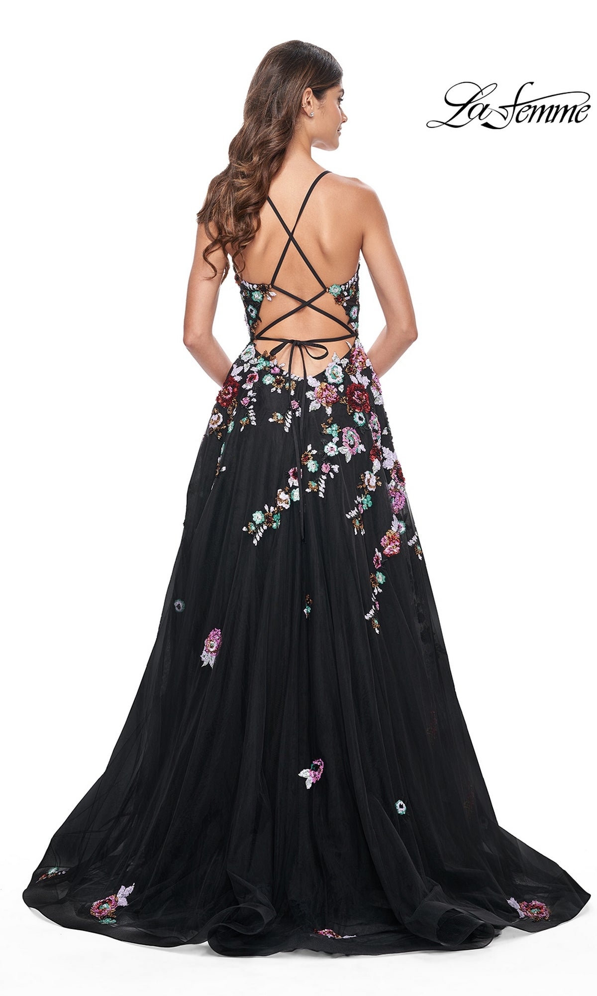 A woman models the La Femme Floral-Sequin Long Black Prom Dress 32051, featuring sequin flowers and a strappy open back, against a white background.