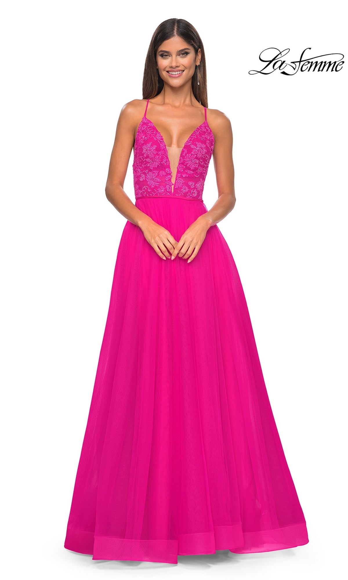 A woman smiles in the La Femme Deep V-Neck Long Tulle Prom Gown 32059, featuring a sleeveless bright pink lace bodice and deep V-neckline.