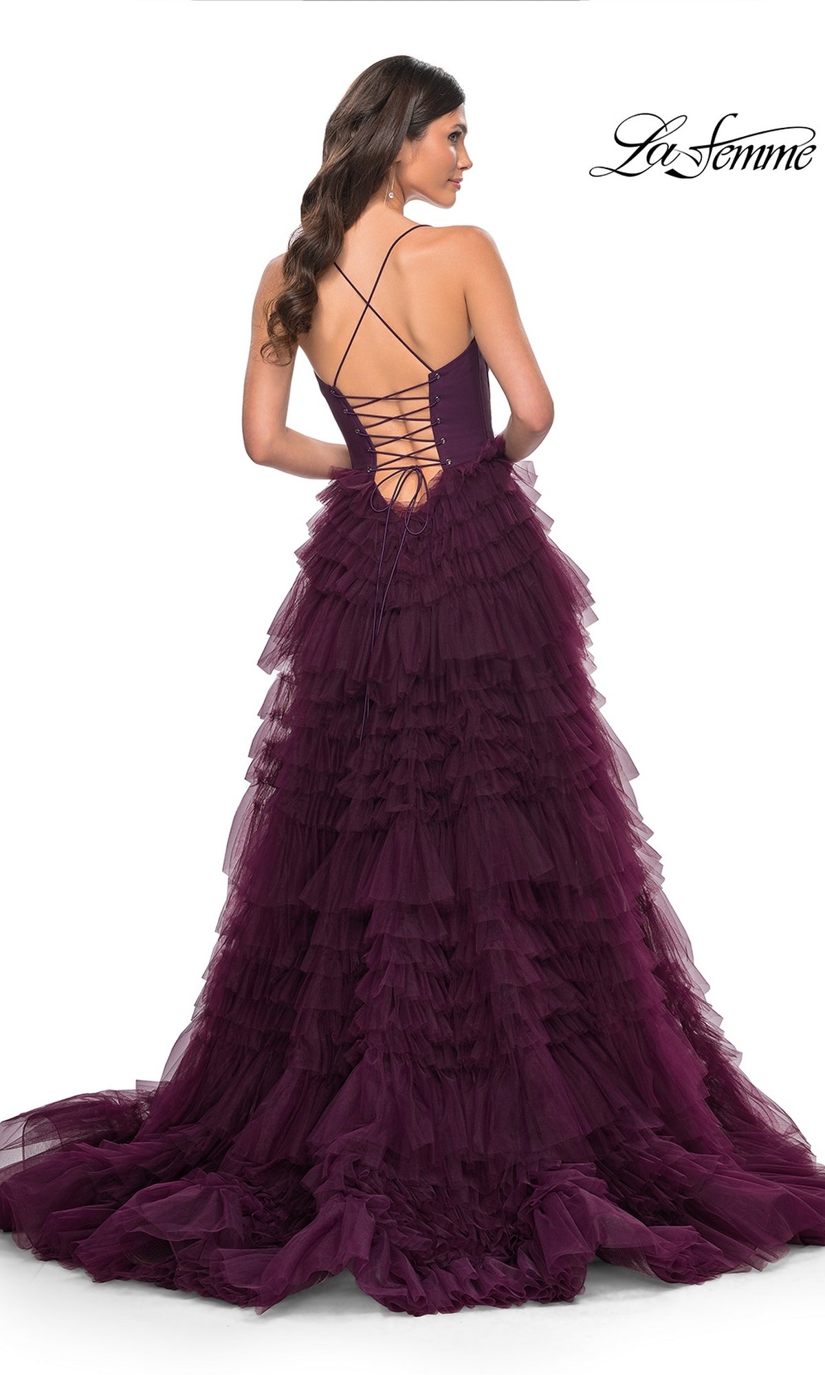A woman faces away in the La Femme 32071 Lace-Up Ruffle Long Prom Ball Gown, featuring a deep purple hue, ruffled A-line skirt, lace-up open back, and sweetheart corset bodice against a white background.