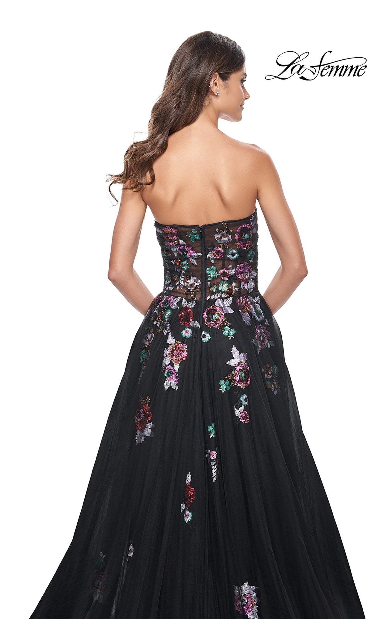 Woman wearing the Le Femme Sequin-Floral Long Black Prom Dress 32072, featuring multicolored sequin floral embroidery and a strapless design, shown from the back with the