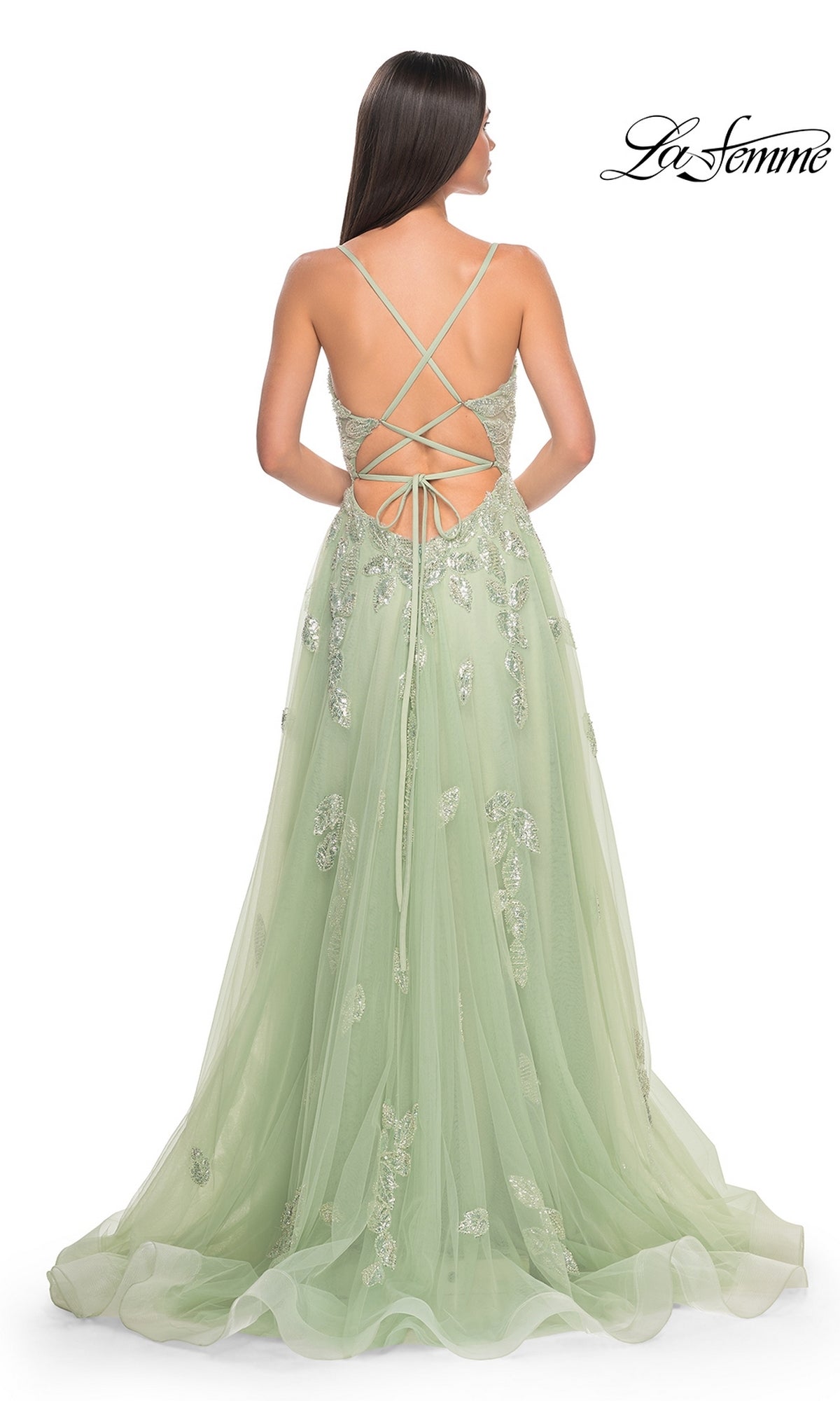 Woman wearing the La Femme Sequin-Embroidered Long Prom Dress 32090 in light green, featuring floral embellishments, sequin embroidery, and a lace-up open back, standing against a white background.