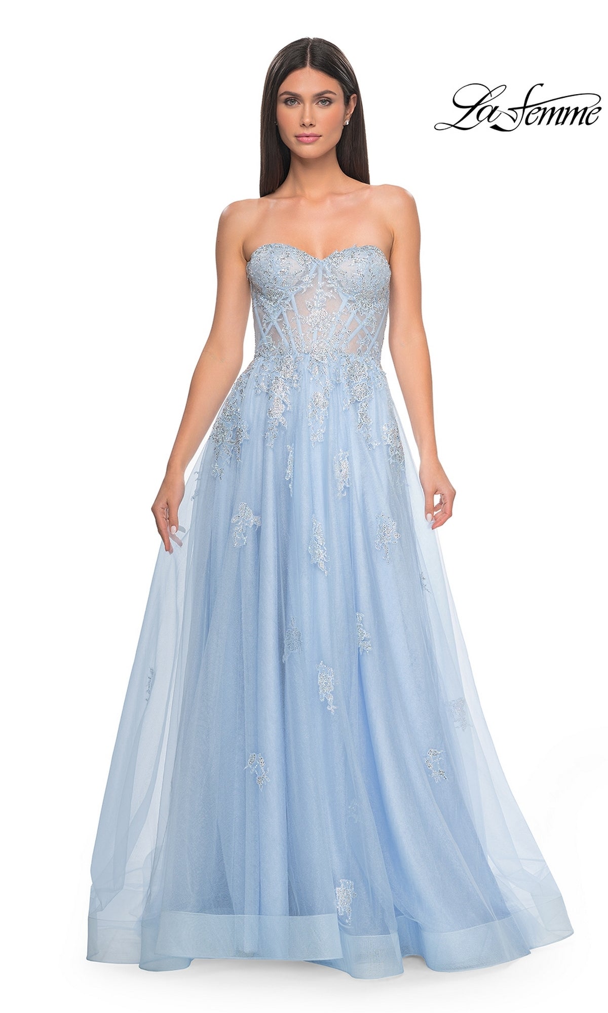 A woman stands against a white background wearing the La Femme Strapless Long A-Line Prom Dress 32111 in light blue, featuring a sheer bodice with silver embroidered-lace appliques.