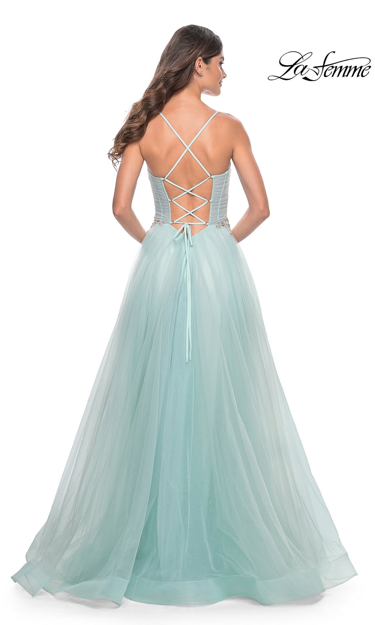 A woman is photographed from behind in a light blue La Femme Sheer-Bodice Long A-Line Prom Dress 32117 with spaghetti straps and an open-back, set against a white background.
