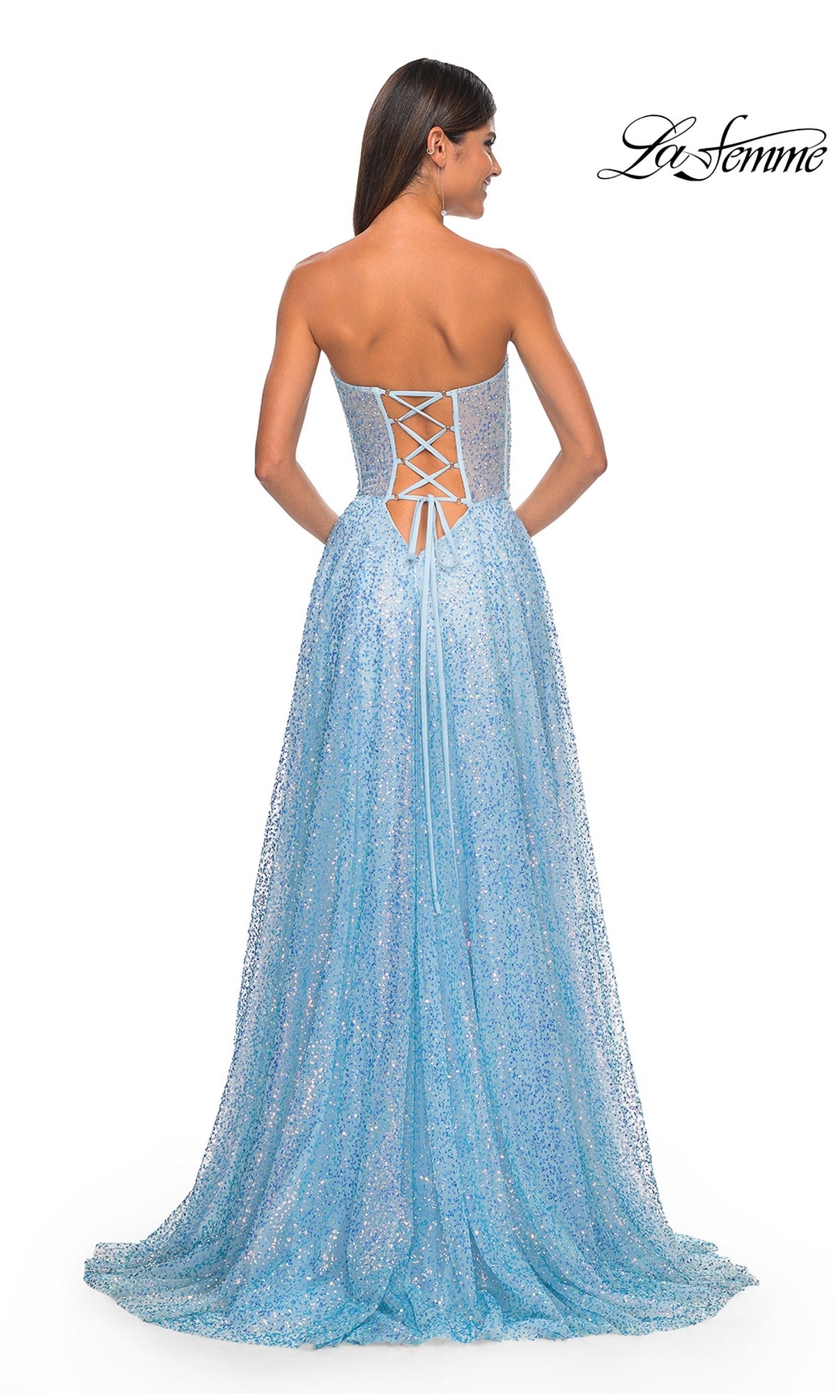 A woman stands with her back to the camera in the La Femme Strapless Embellished Prom Dress 32136, a glittery light blue A-line gown featuring a lace-up back, hot-stone accents for extra sparkle, and a slight train.
