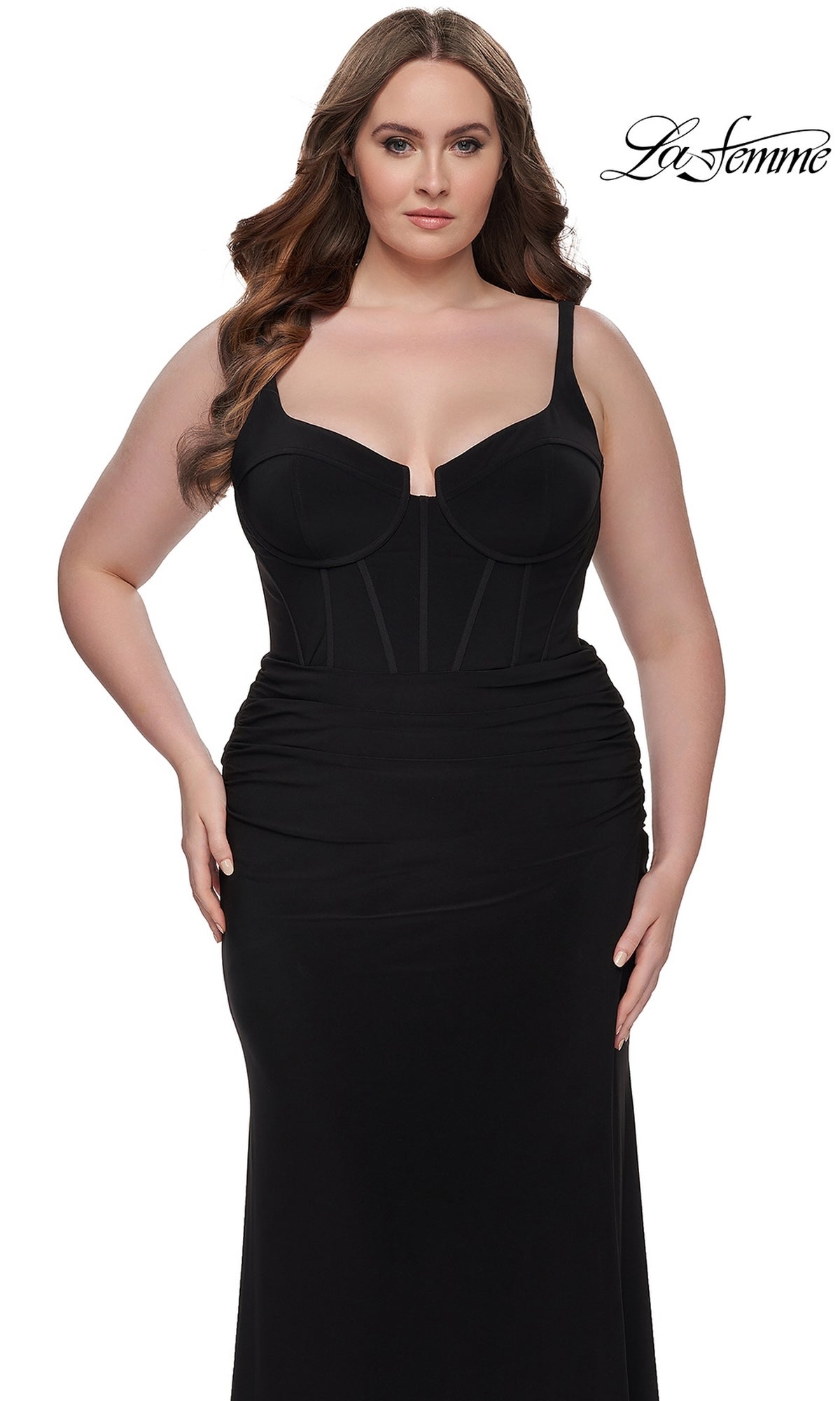A woman with long brown hair models the La Femme Plus-Size Long Lace-Up Prom Dress 32190, a fitted black gown with a structured bodice and ruching at the hips, standing against a white background. The La Femme logo appears in the top right corner.