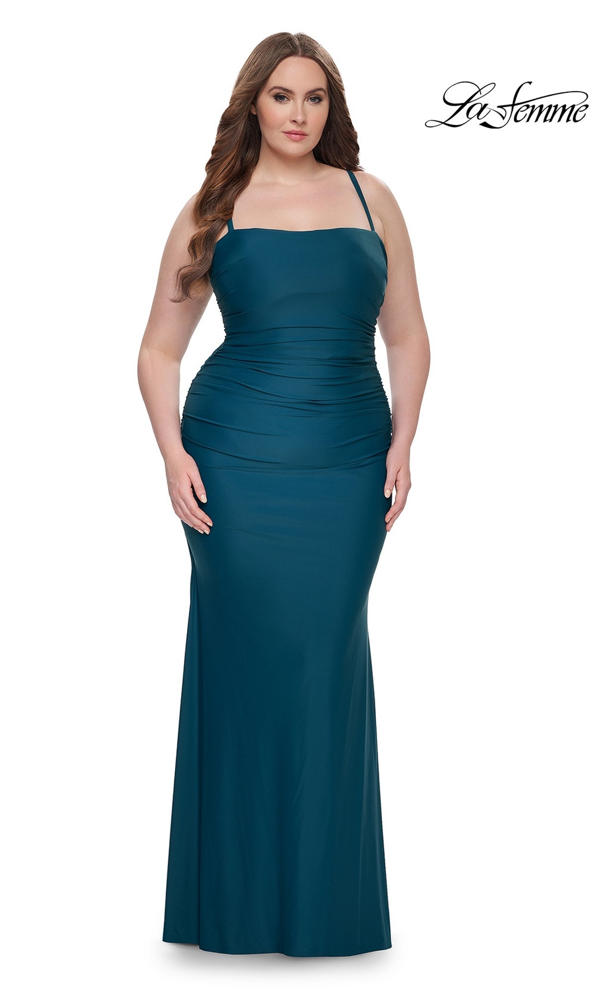 A woman wearing the La Femme Plus-Size Lace-Up Long Prom Dress 32195 in teal, sleeveless and floor-length with waist ruching, stands against a plain white background.
