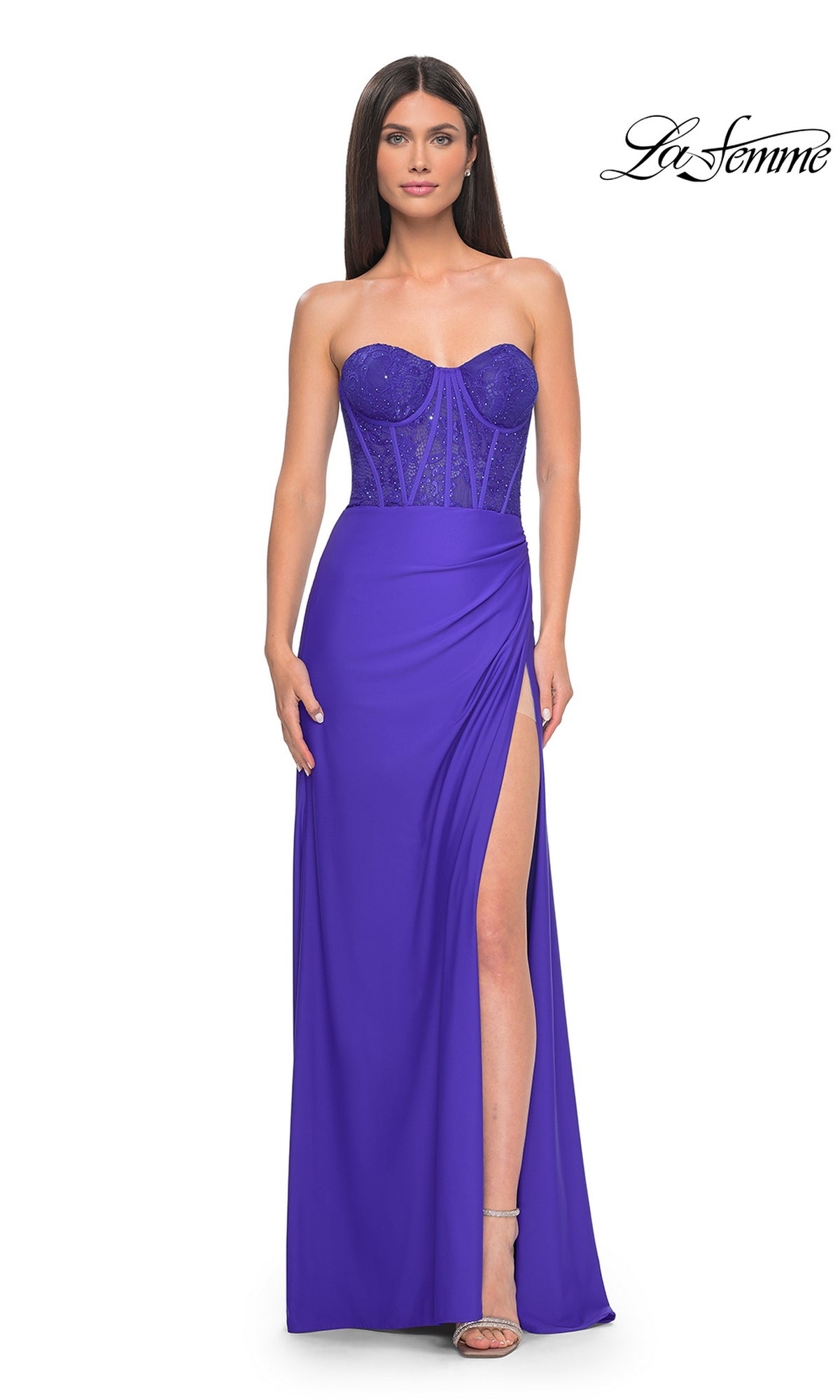 A woman models the La Femme Strapless Long Corset Prom Dress 32234 in royal blue, featuring a sparkly embellished corset, sheer bodice details, high slit, and silver heels.