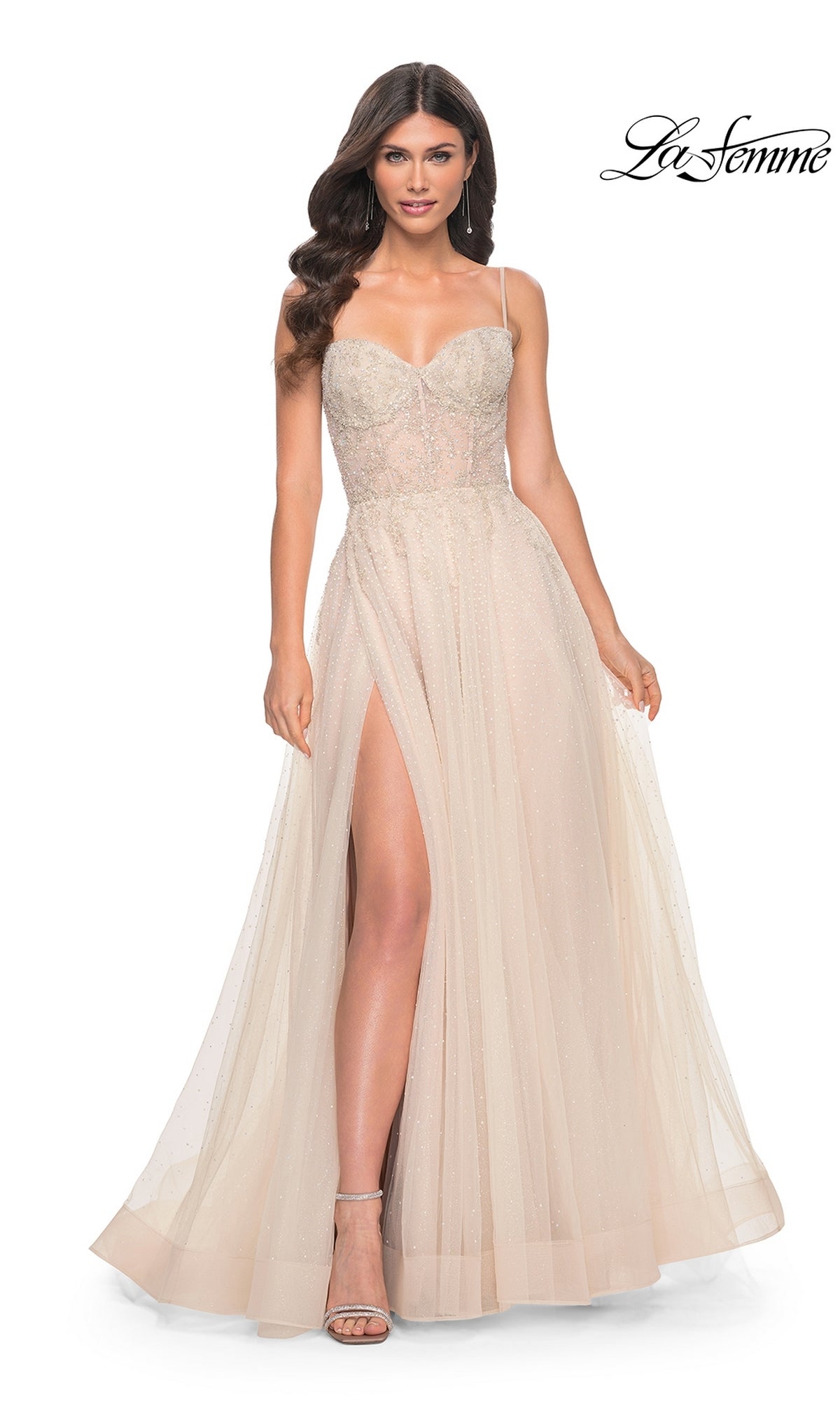 A woman wears the La Femme Champagne Long A-Line Prom Dress 32271, featuring spaghetti straps, a fitted bodice, and a high leg slit, standing against a white background with the 'La Femme' logo in the upper right corner.